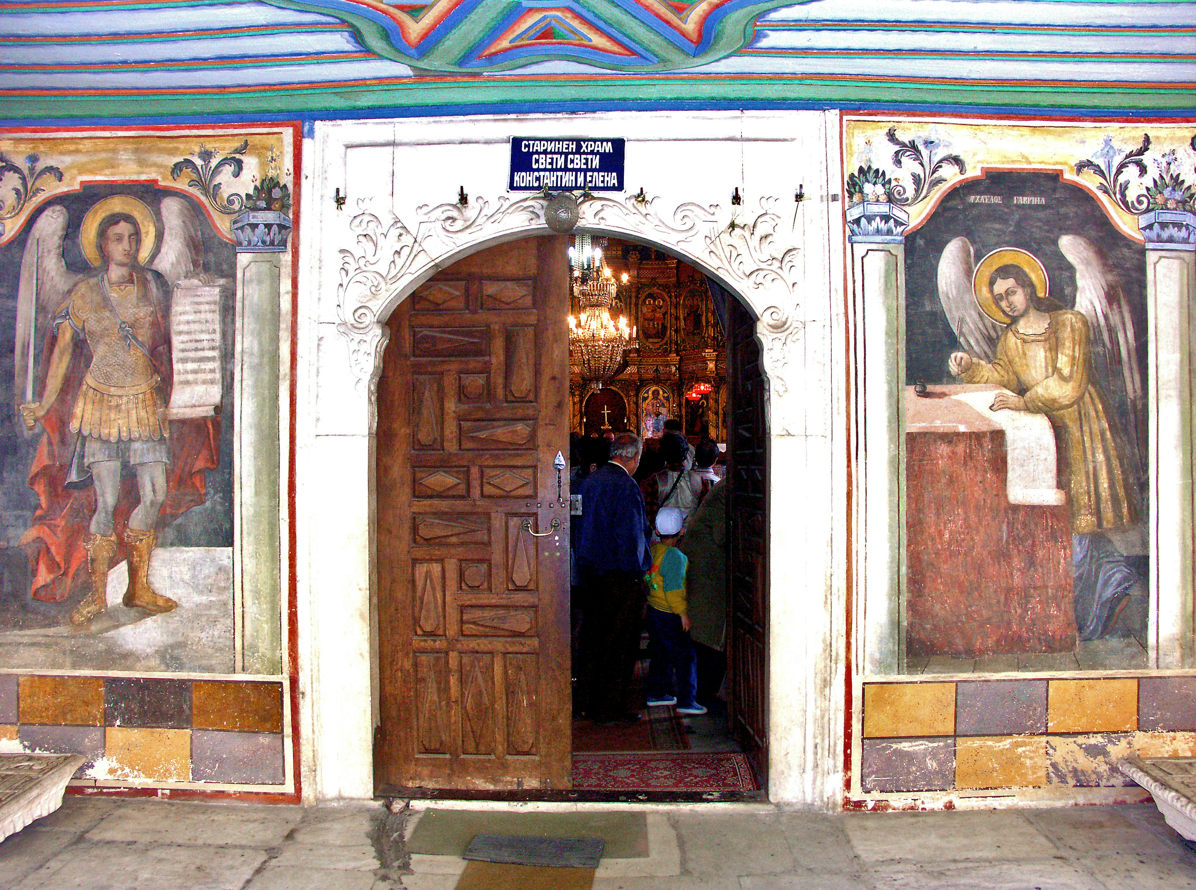 Image of a church entrance with beautiful wall paintings and a wooden door