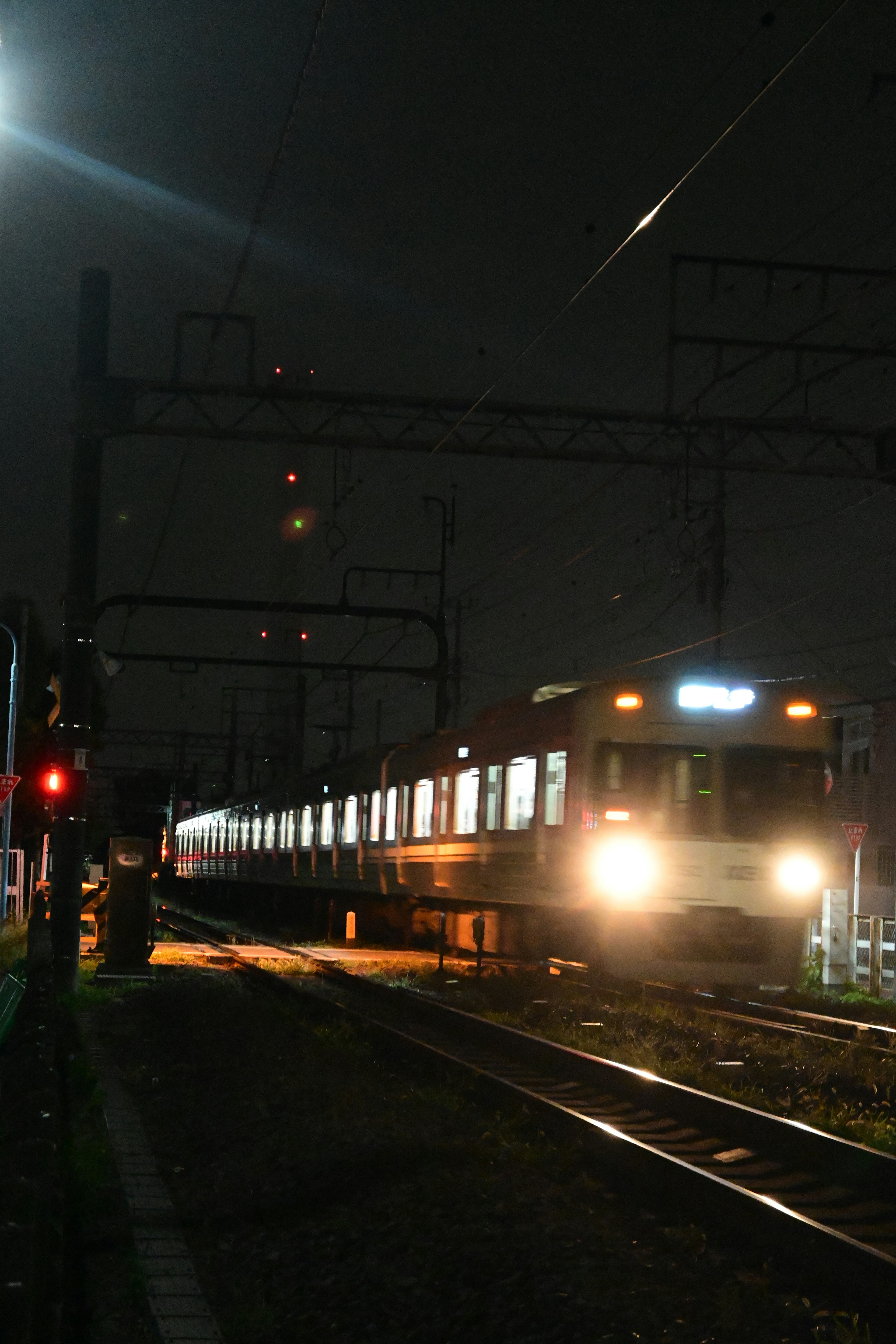 Train in motion at night with bright headlights and red signal