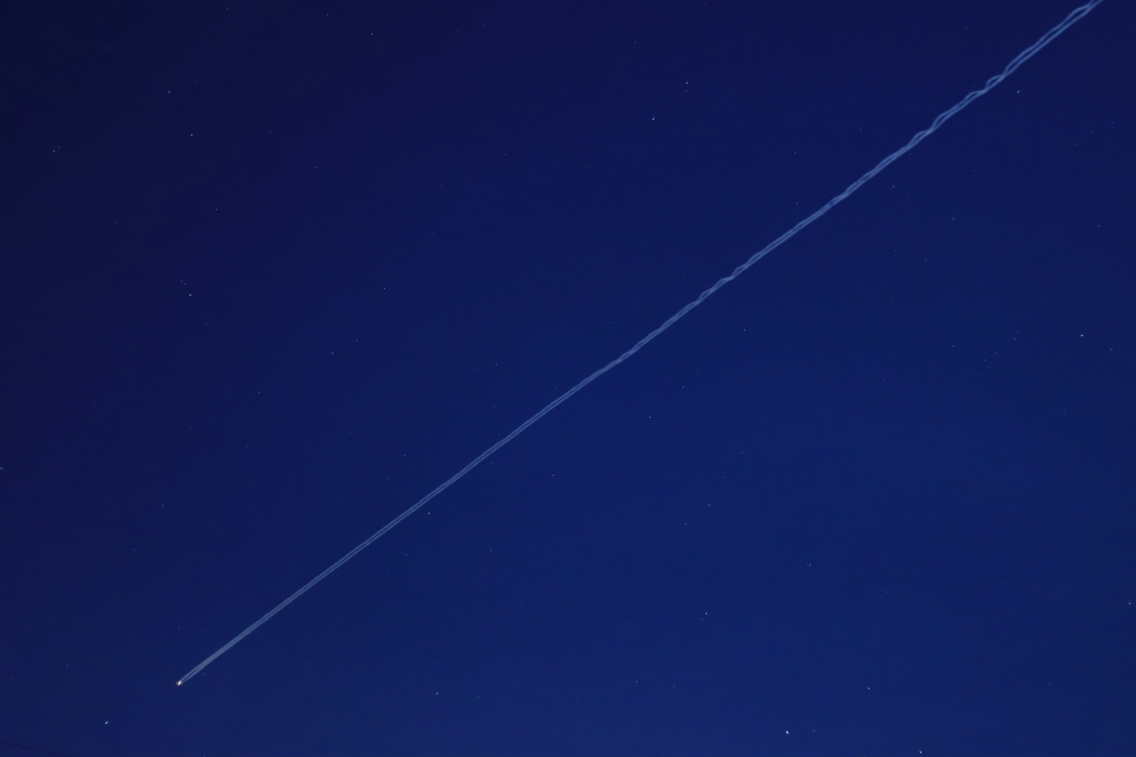 White airplane trail in the night sky