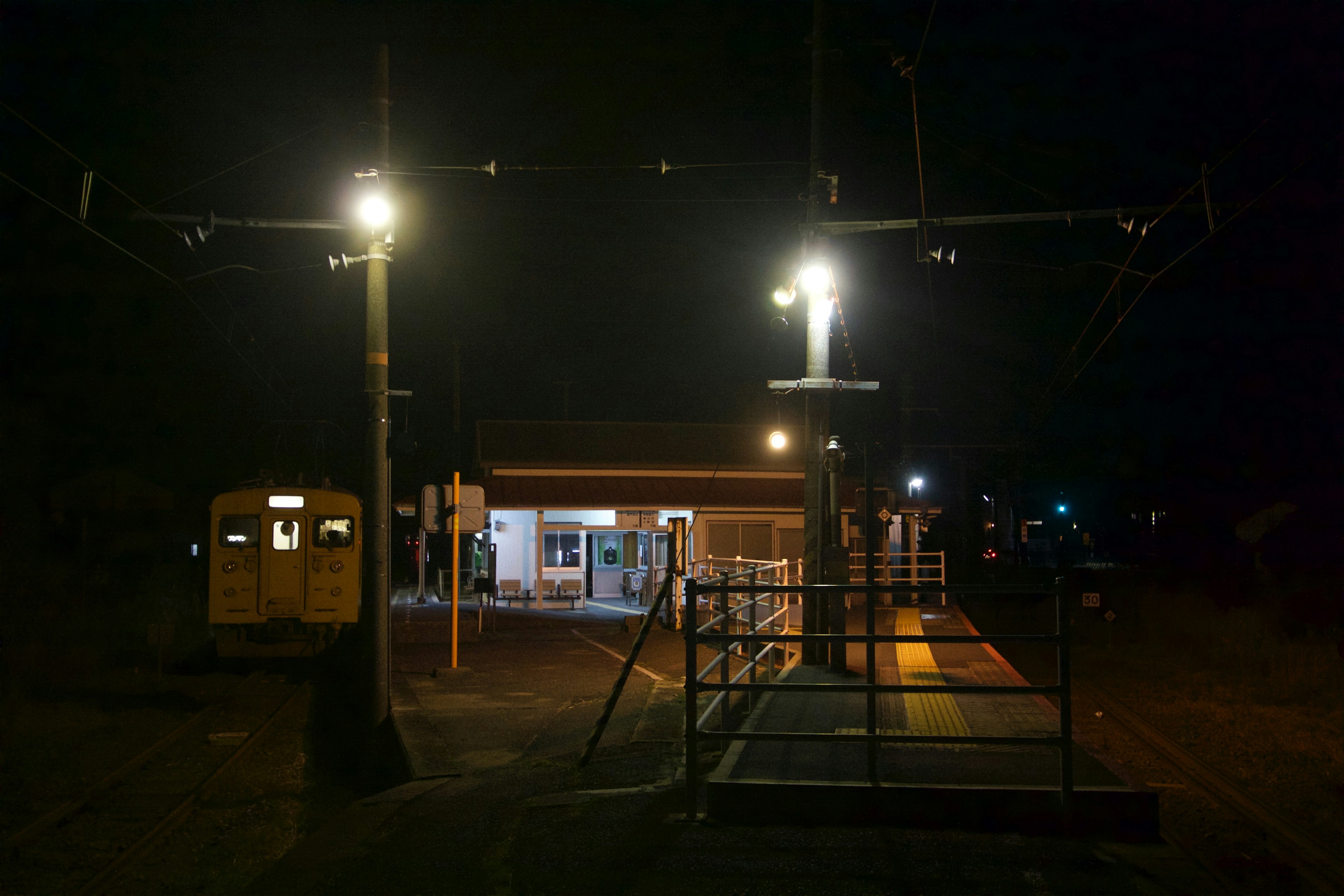 Vista nocturna de una estación de tren con edificio iluminado y luces