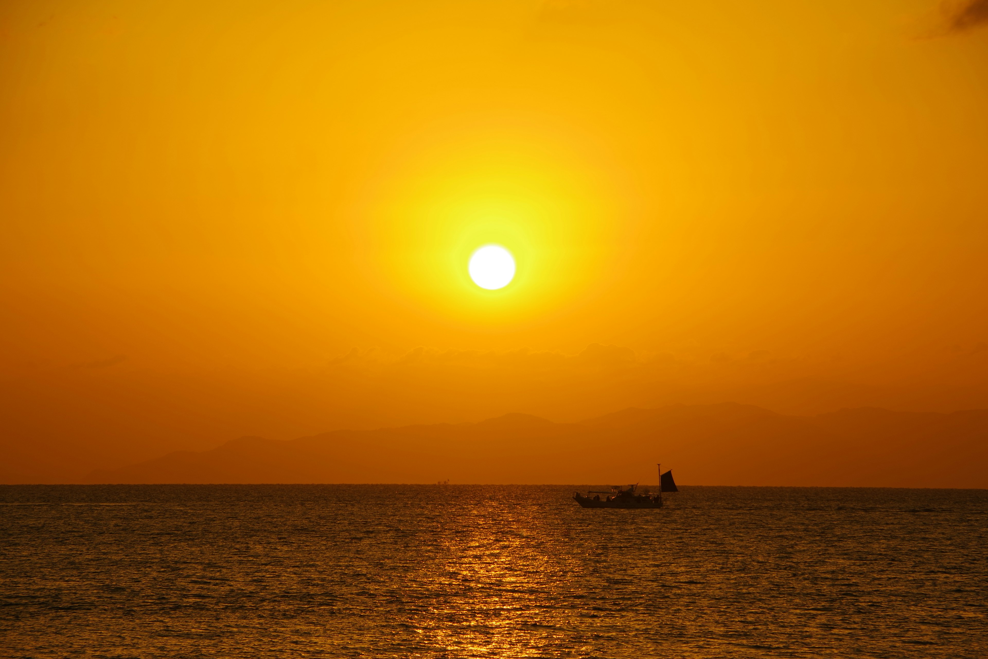 Bellissimo tramonto sull'oceano con una piccola barca sull'acqua