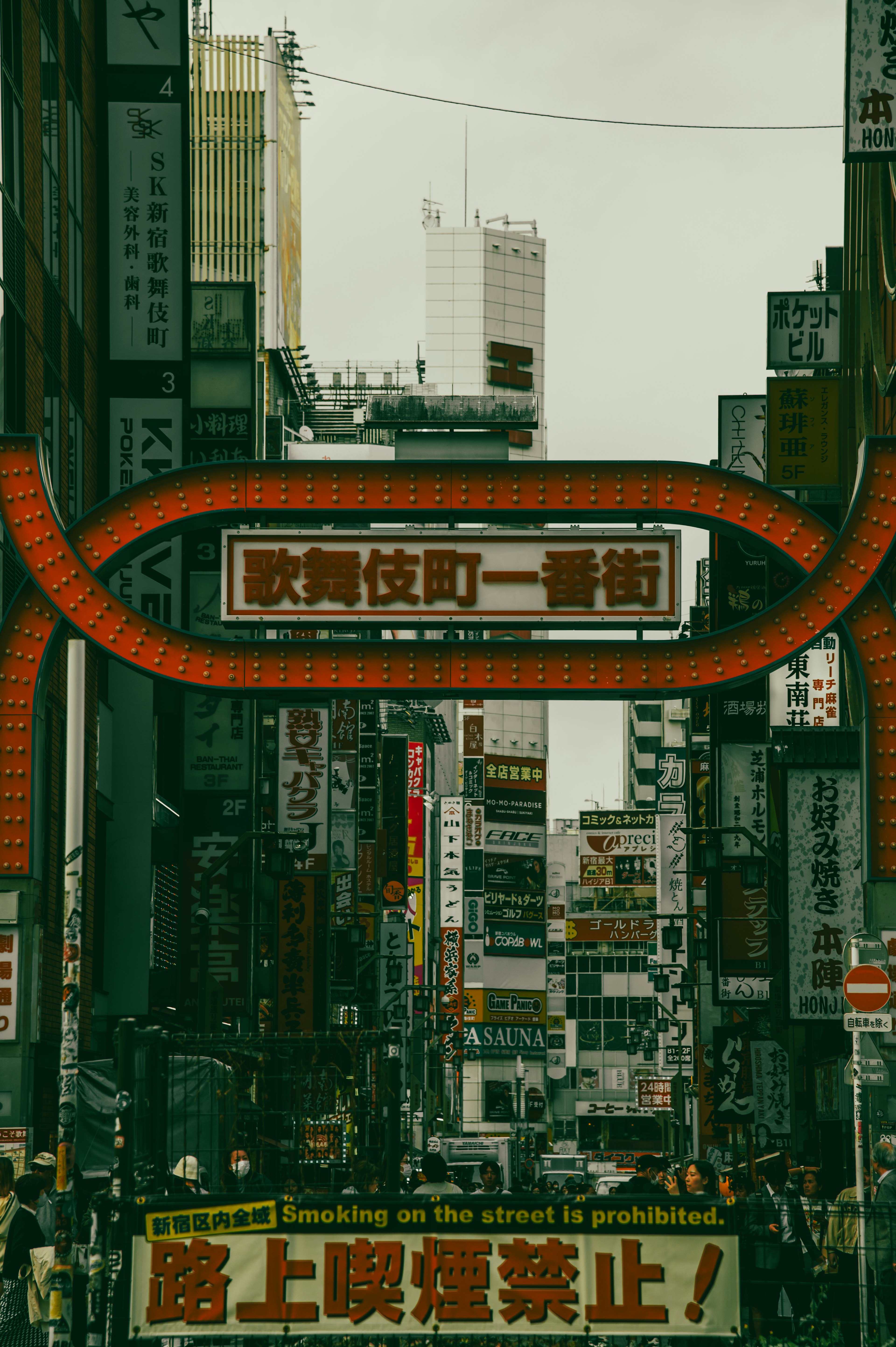 Archway sign over a bustling street with commercial buildings