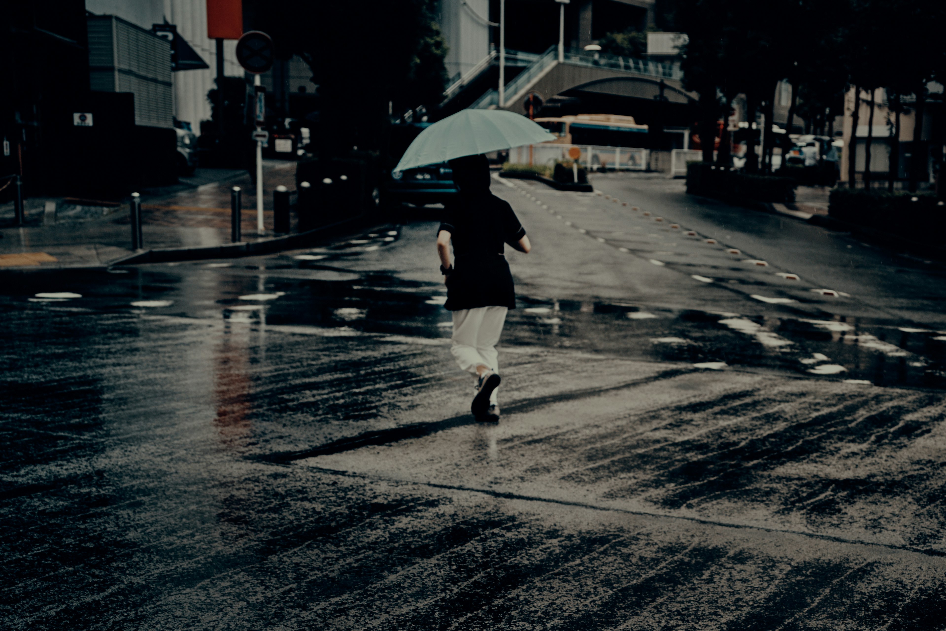 雨の中を走る人が傘を持っている街の風景