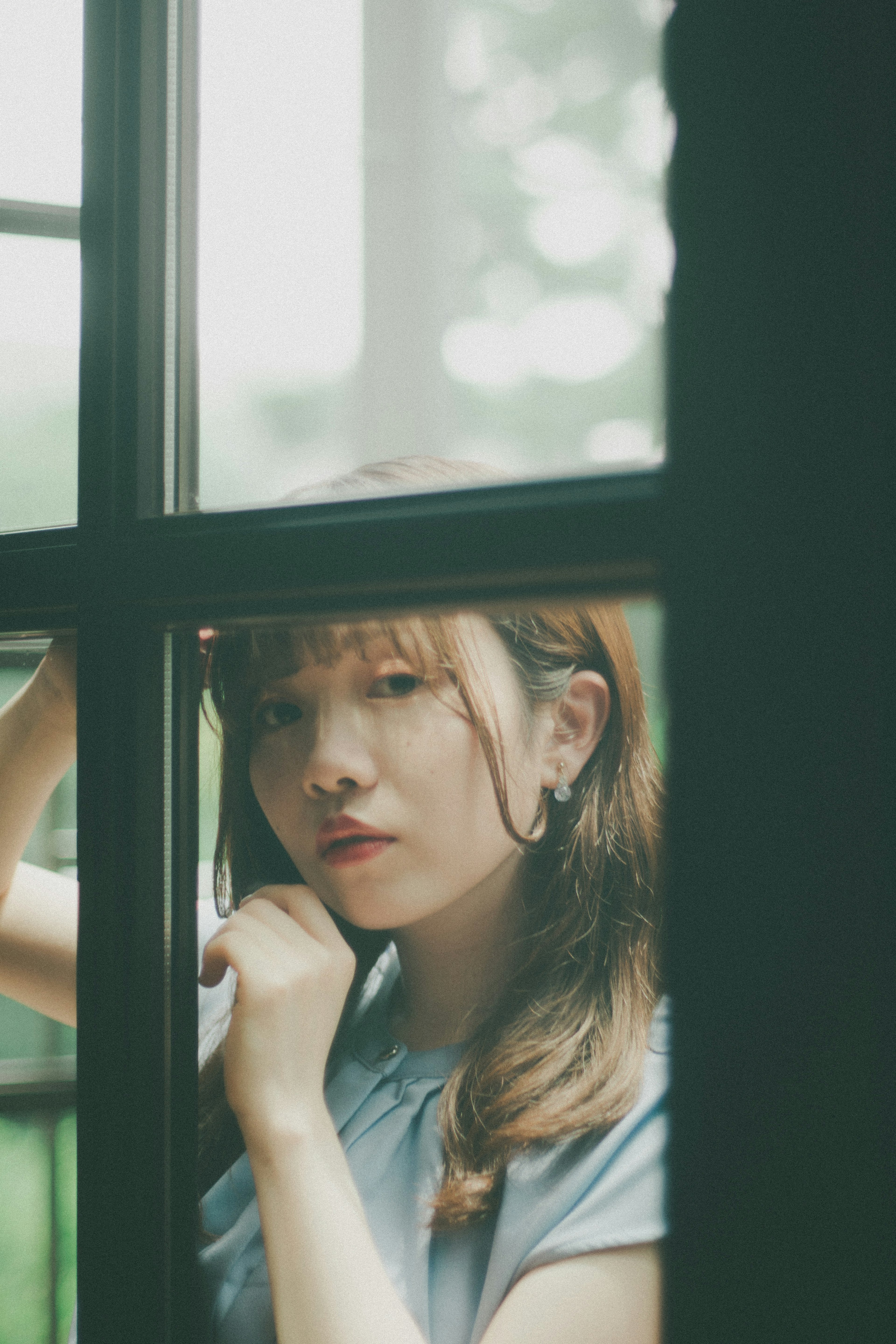 Portrait d'une femme regardant par une fenêtre lumière douce filtrant