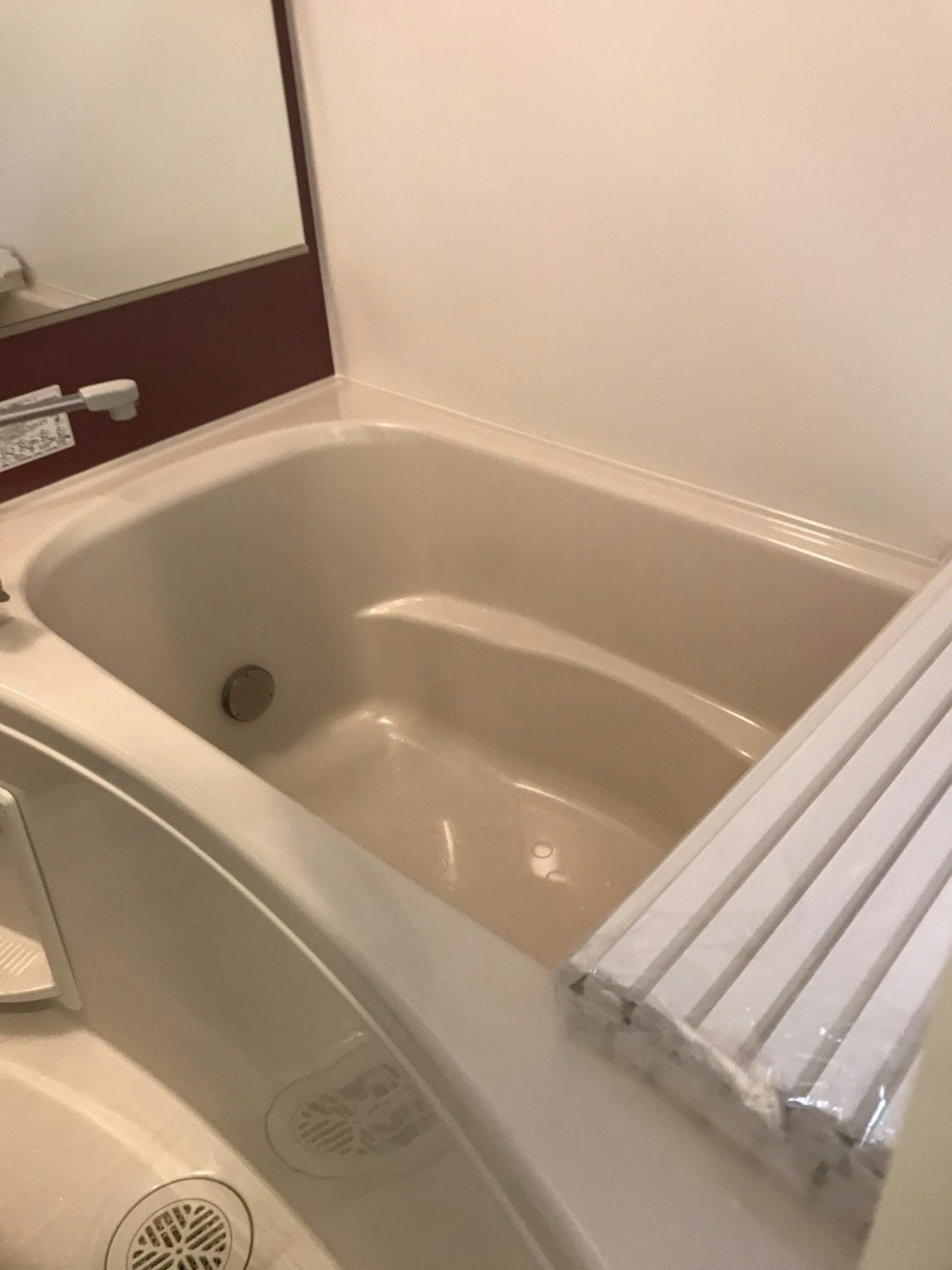 Interior of a simple bathroom featuring a bathtub and mirror