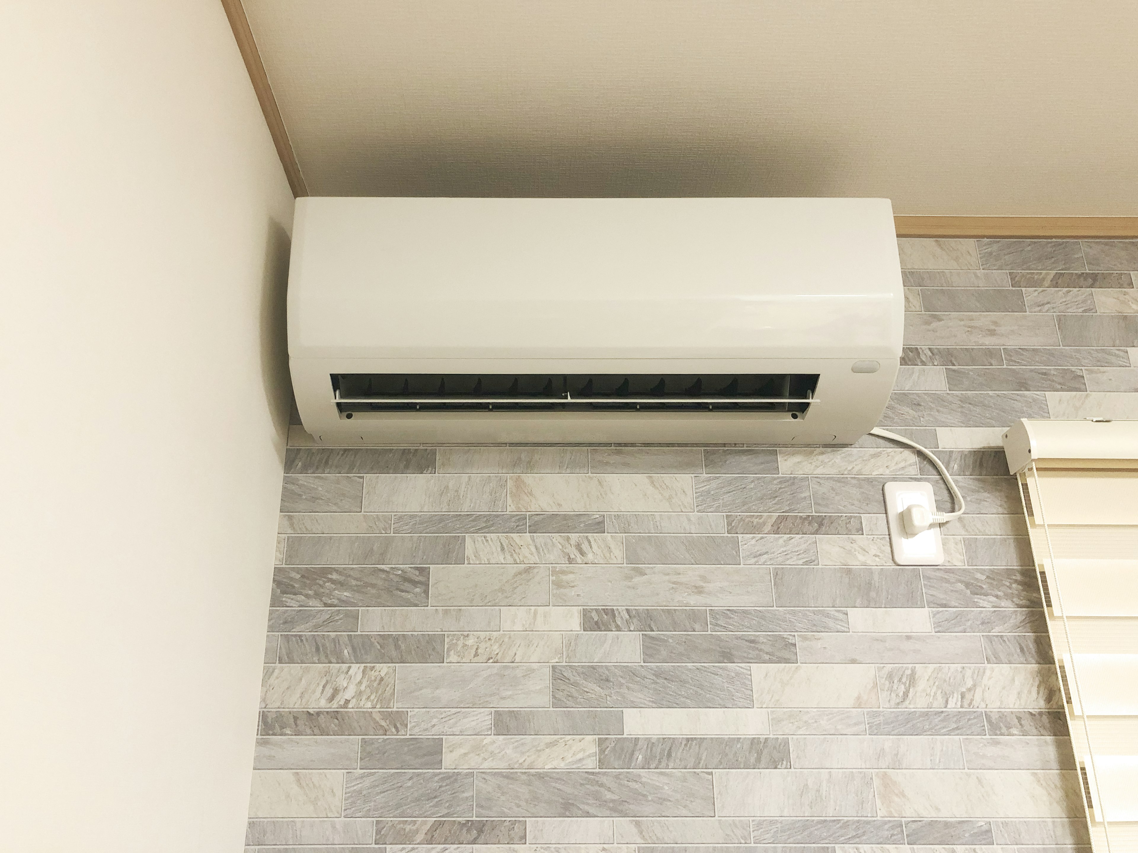 Wall-mounted white air conditioner in a room with gray patterned walls