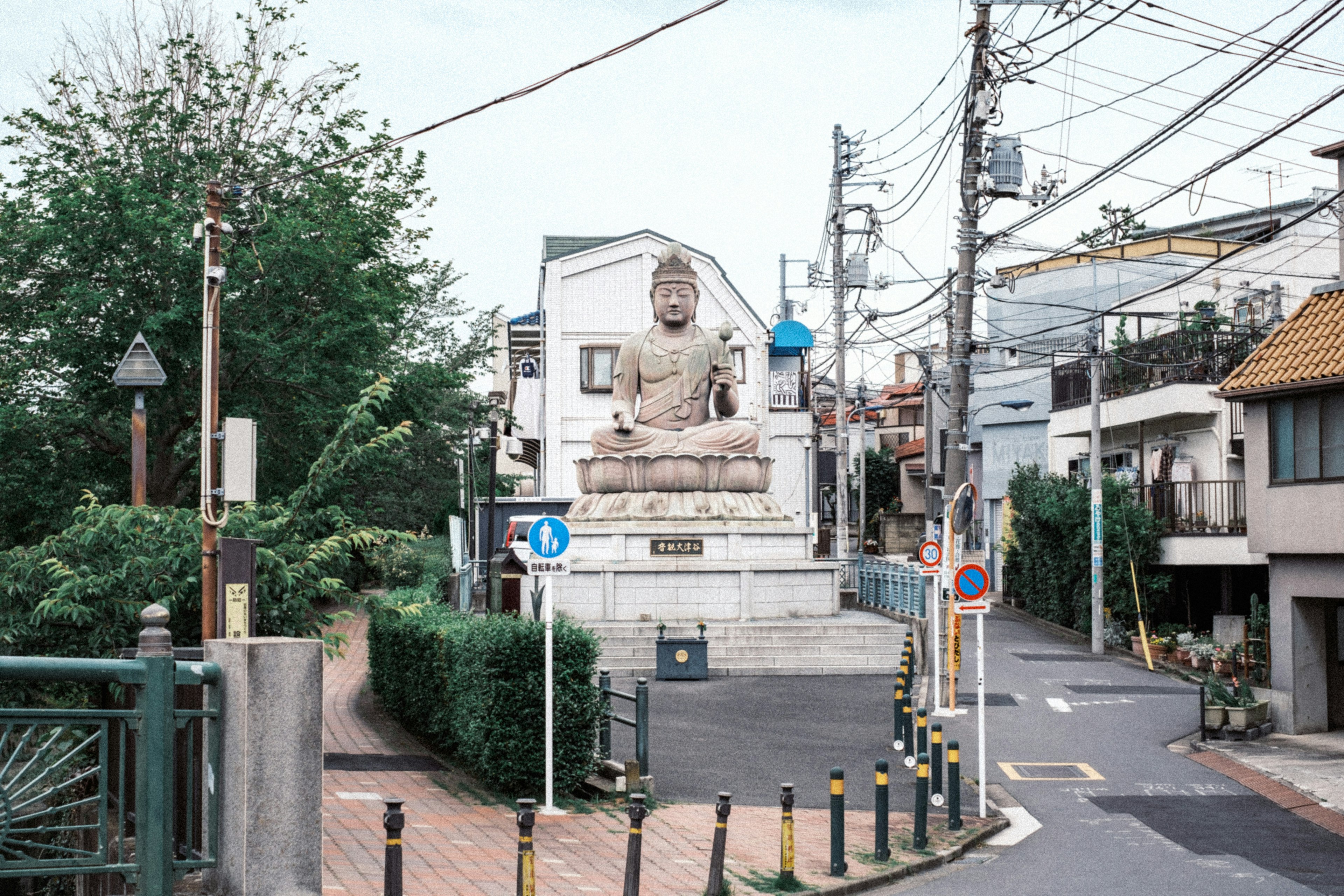 静かな通りに立つ大きな仏像と周囲の建物