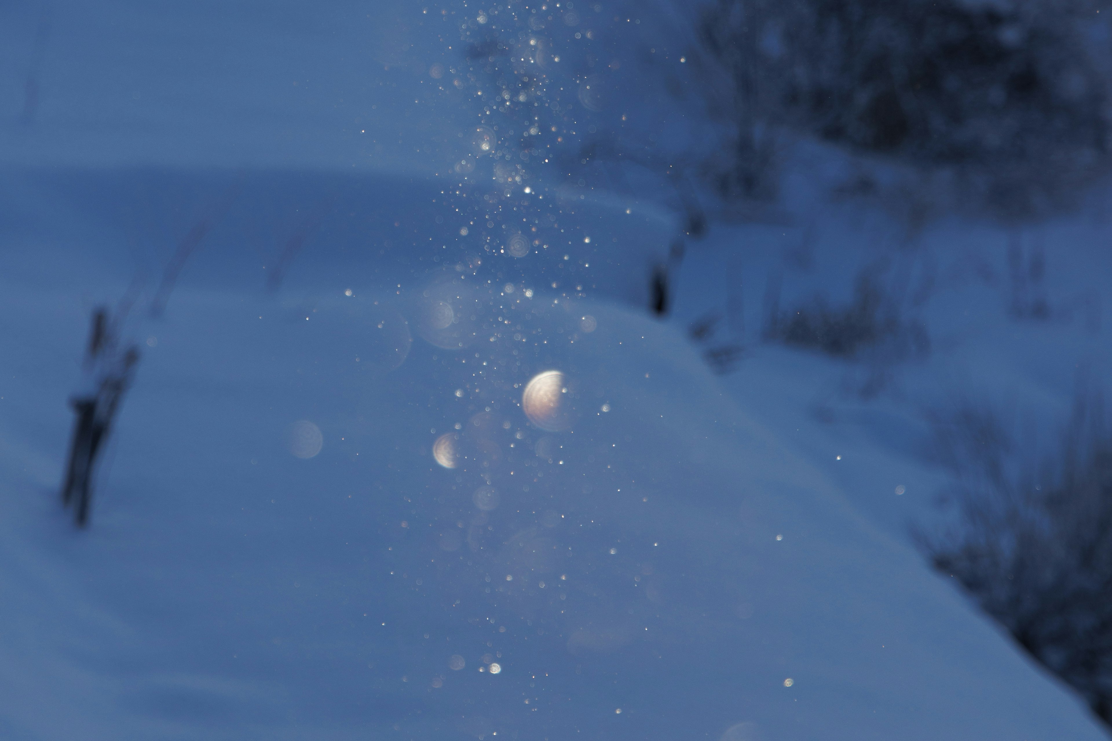 Des particules de neige flottant dans l'air sur un fond bleu