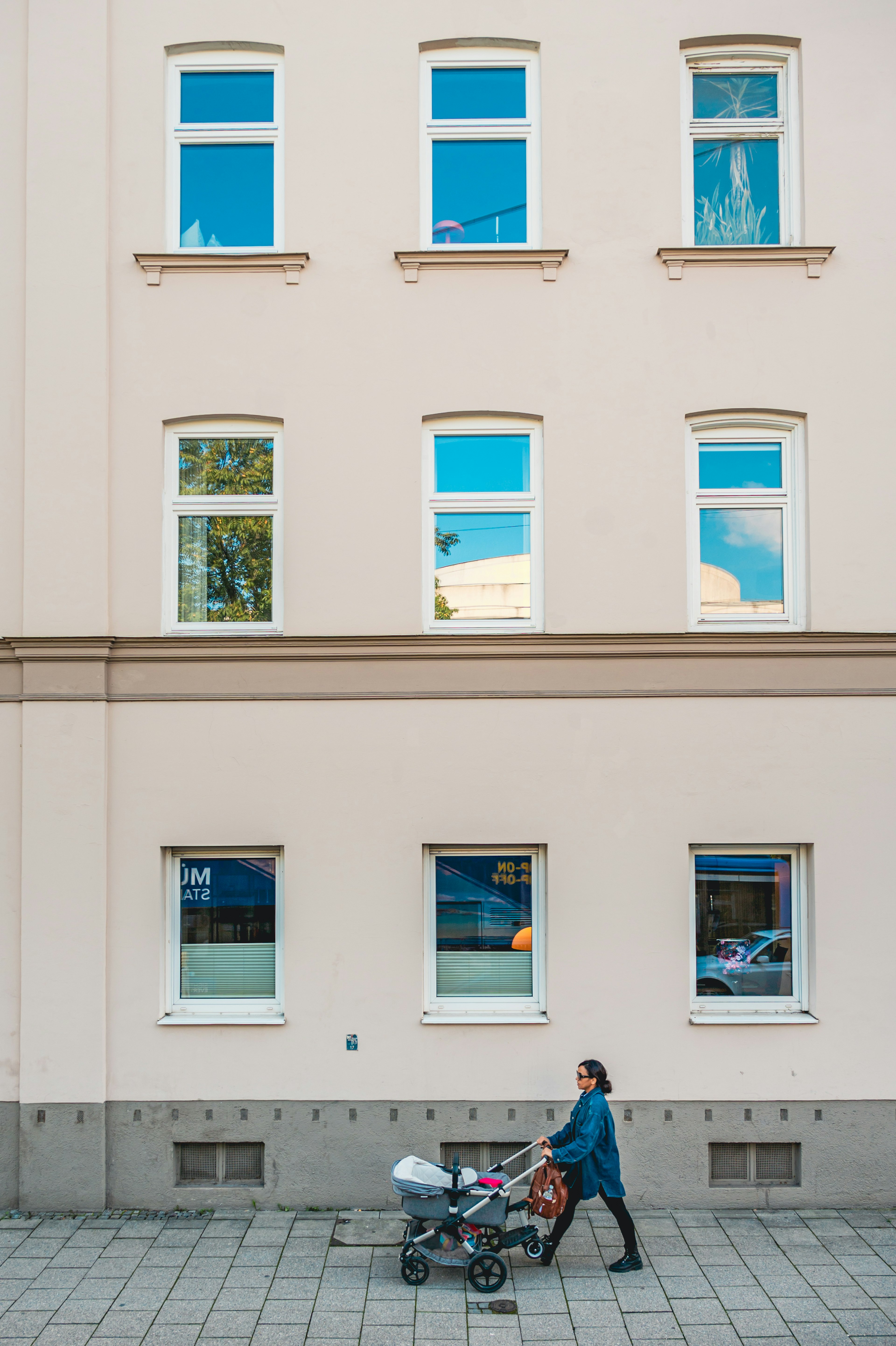 Una donna che spinge un passeggino davanti a un edificio con diverse finestre