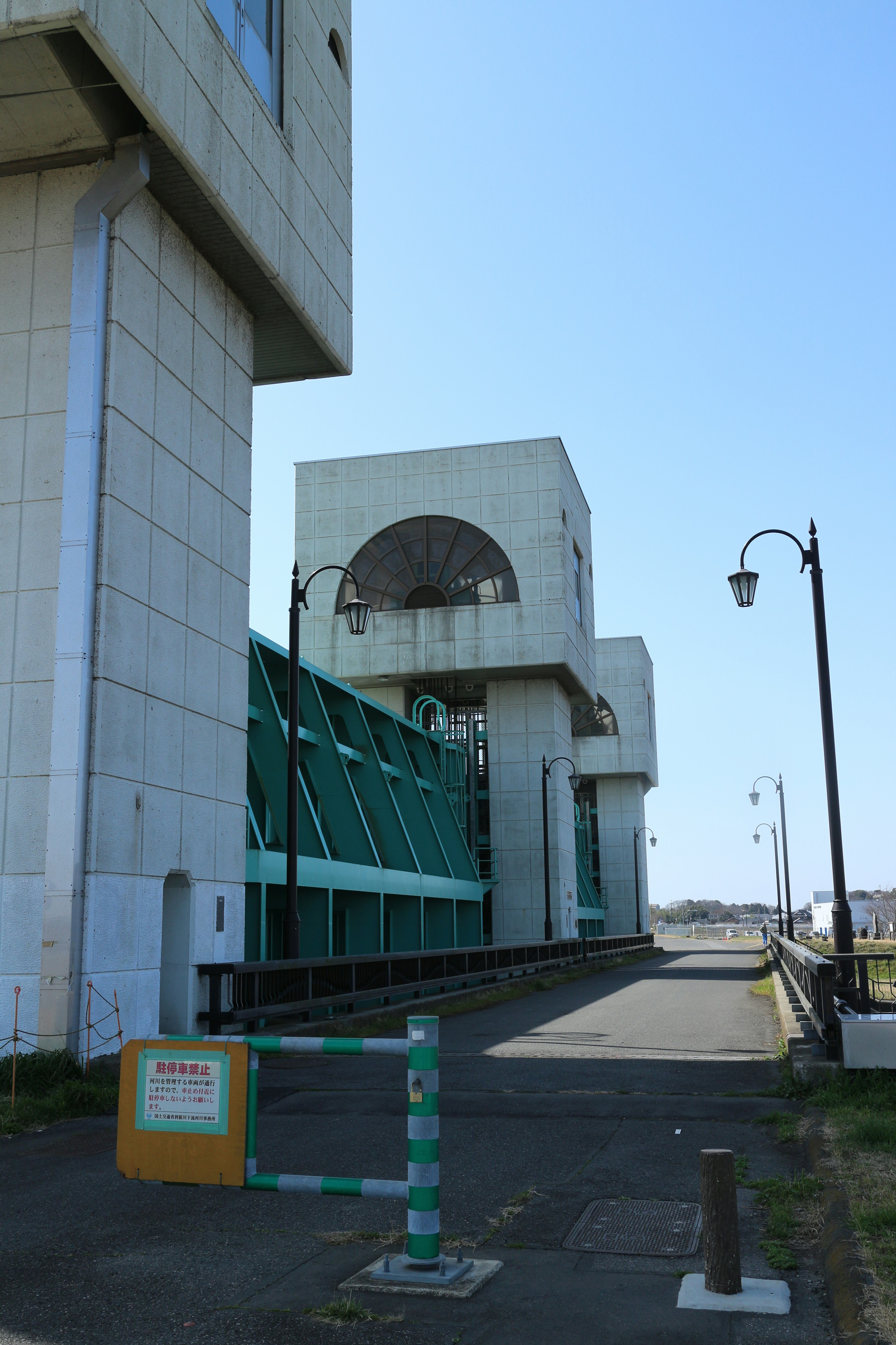 Extérieur d'un bâtiment moderne sous un ciel bleu avec une structure verte et des murs blancs