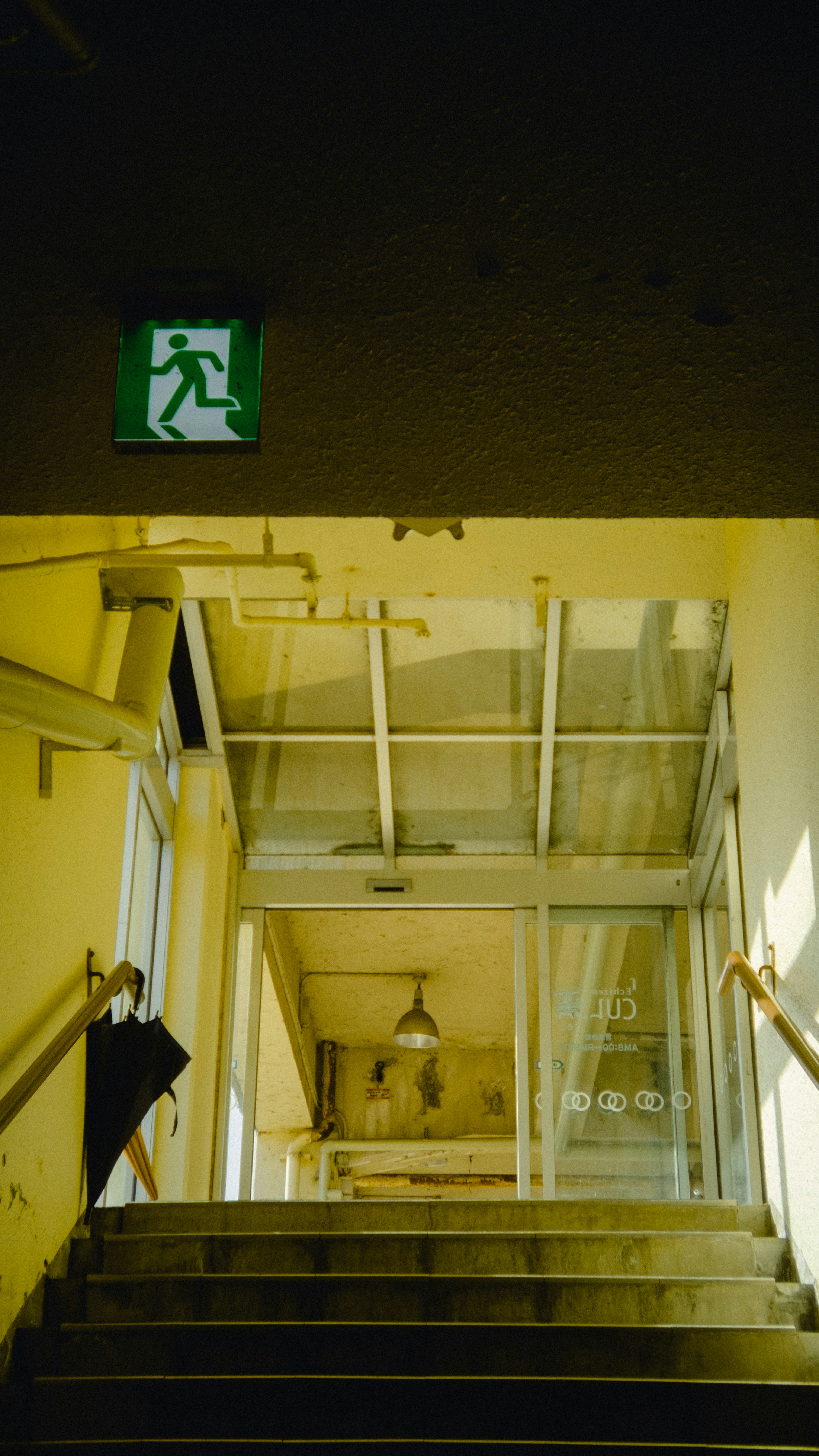 Una persona bajando escaleras con una señal de salida de emergencia en un espacio brillante