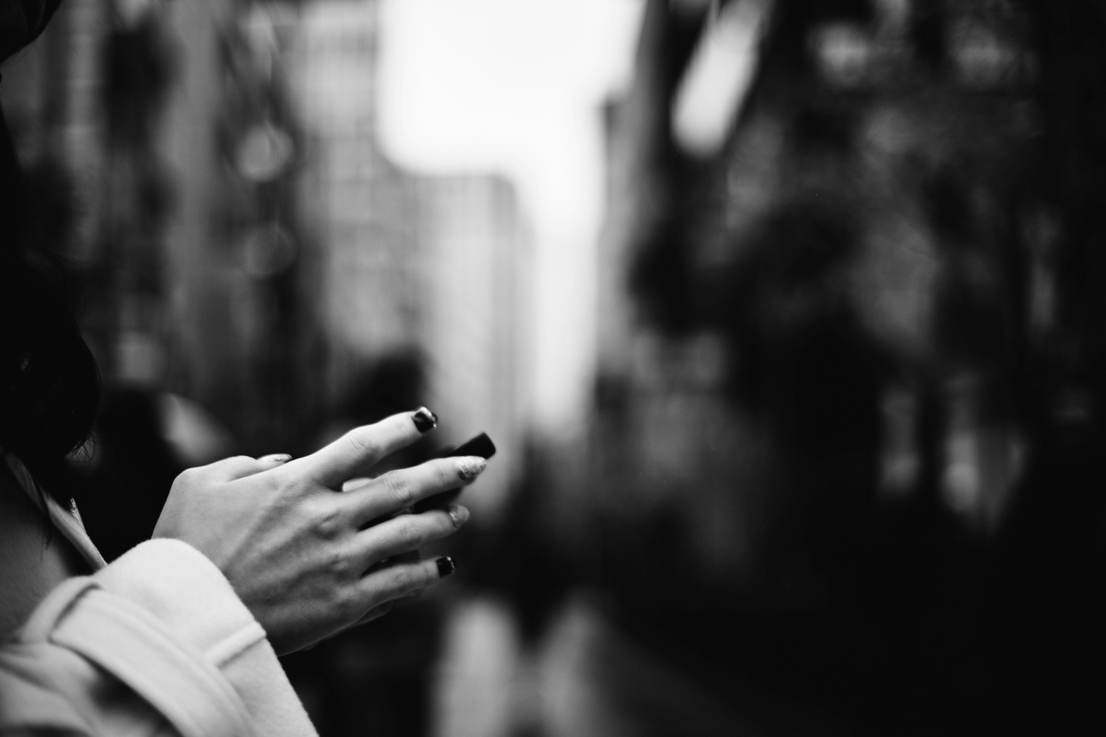 Foto en blanco y negro de la calle con manos sosteniendo un smartphone