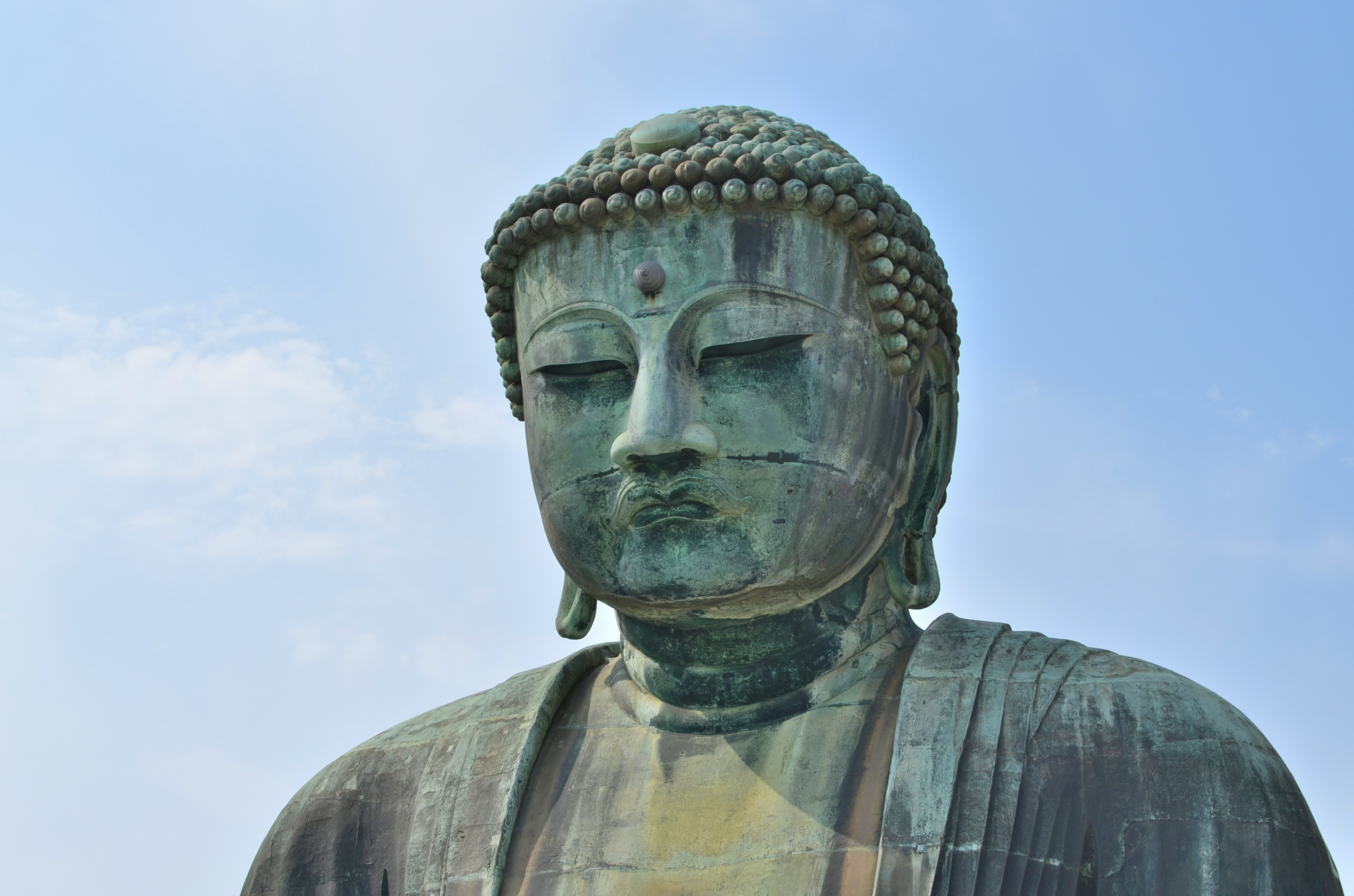 Close-up of a bronze Buddha statue against a blue sky