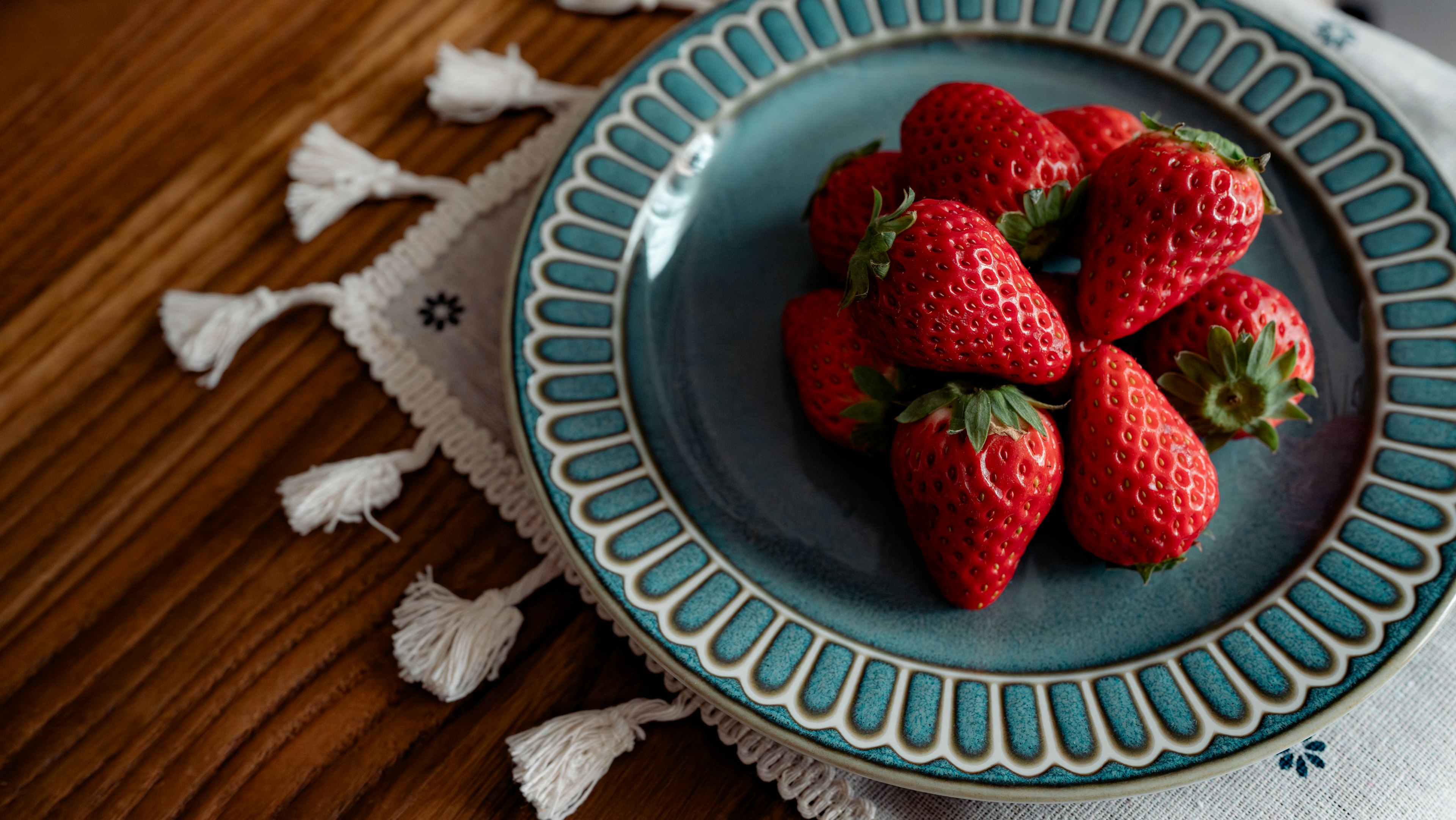 Fresh strawberries arranged on a blue plate with decorative edges