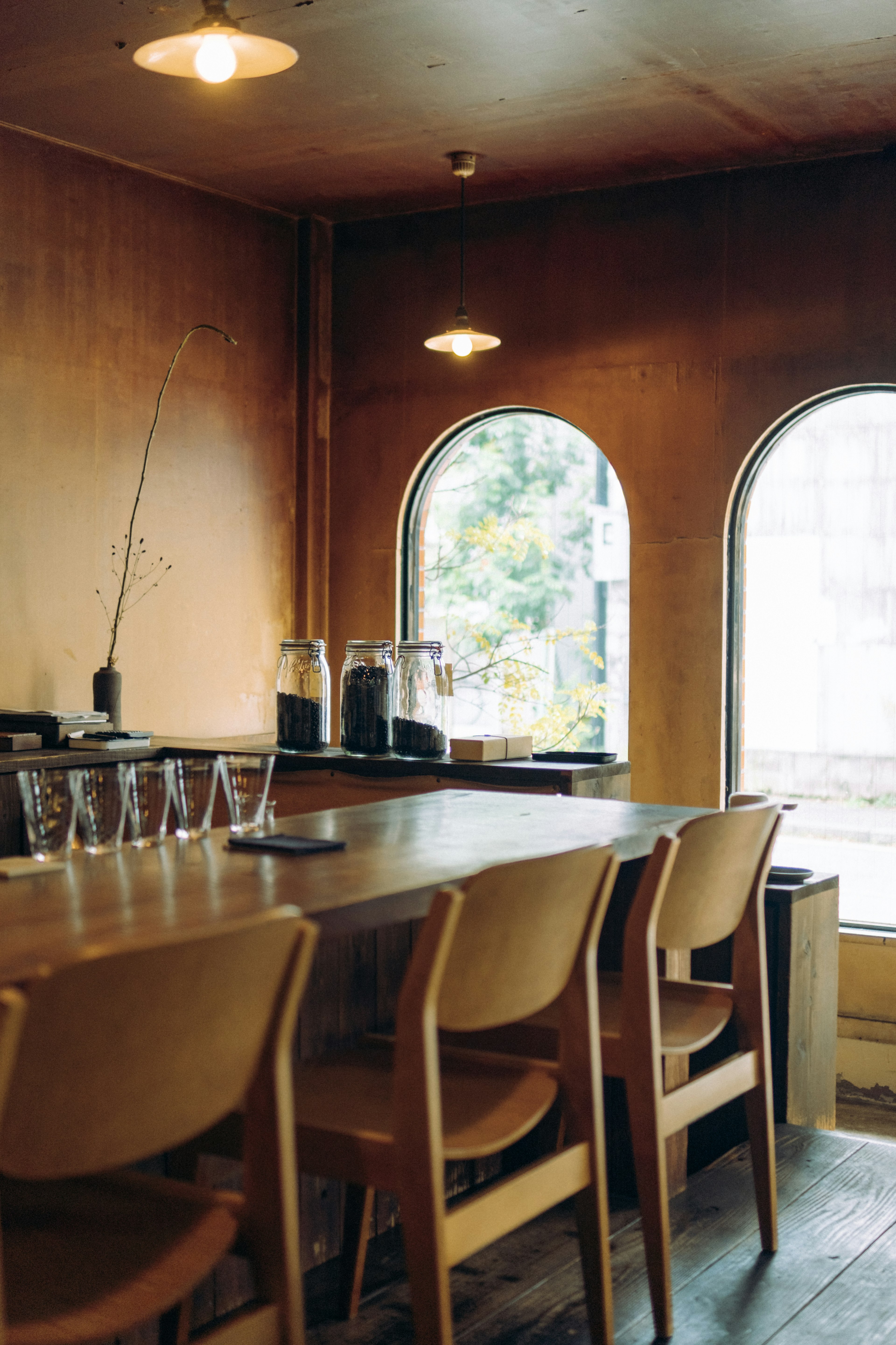 Gemütliches Café-Interieur mit warmen Tönen runden Fenstern Holztheke einfachen Stühlen und Glaswaren