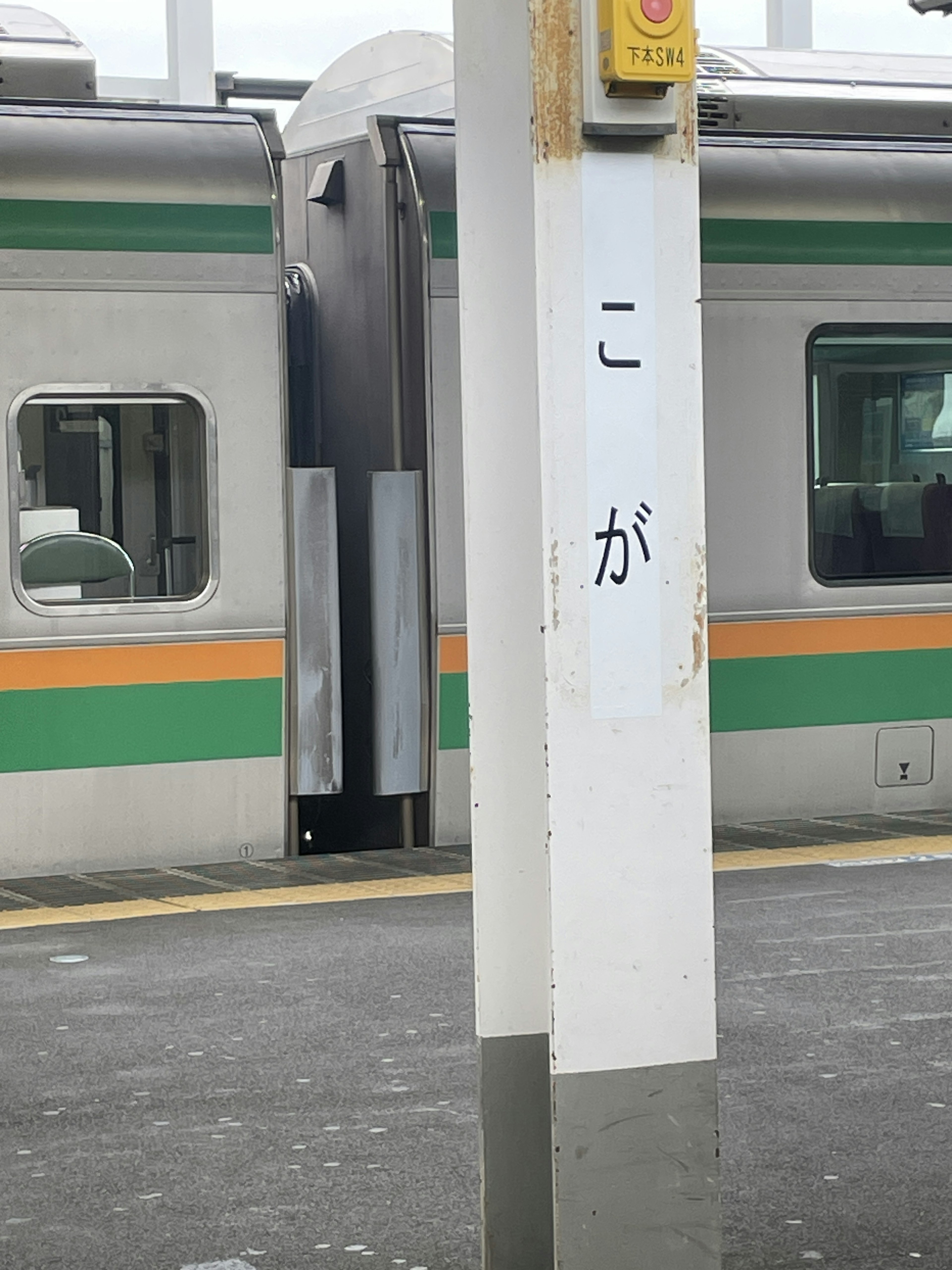 Train arrêté sur un quai de gare avec des caractères japonais sur un pilier