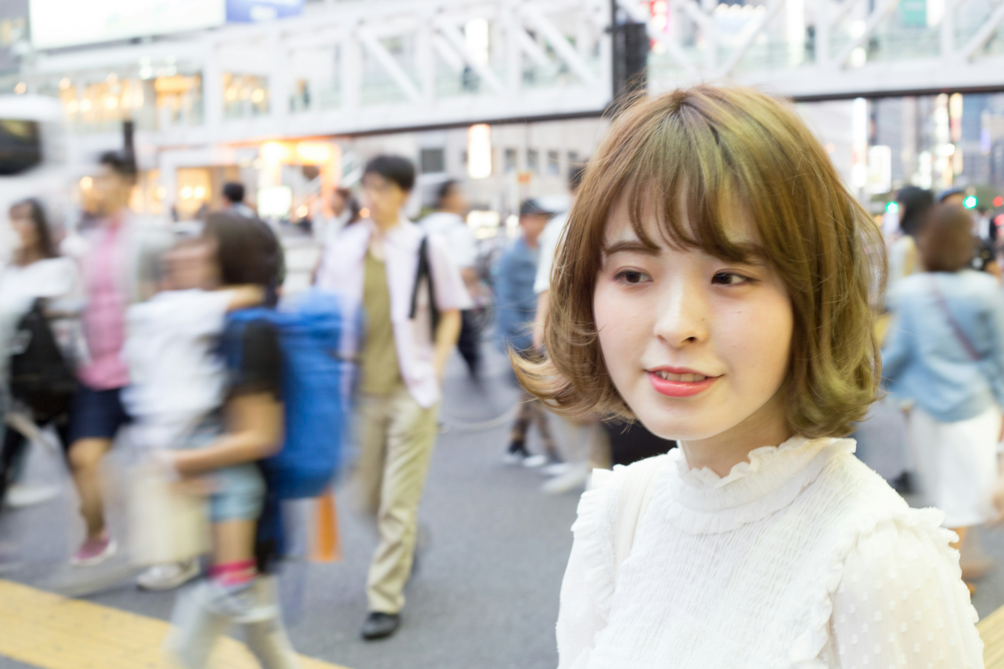 A woman in a white outfit smiling in a busy city street