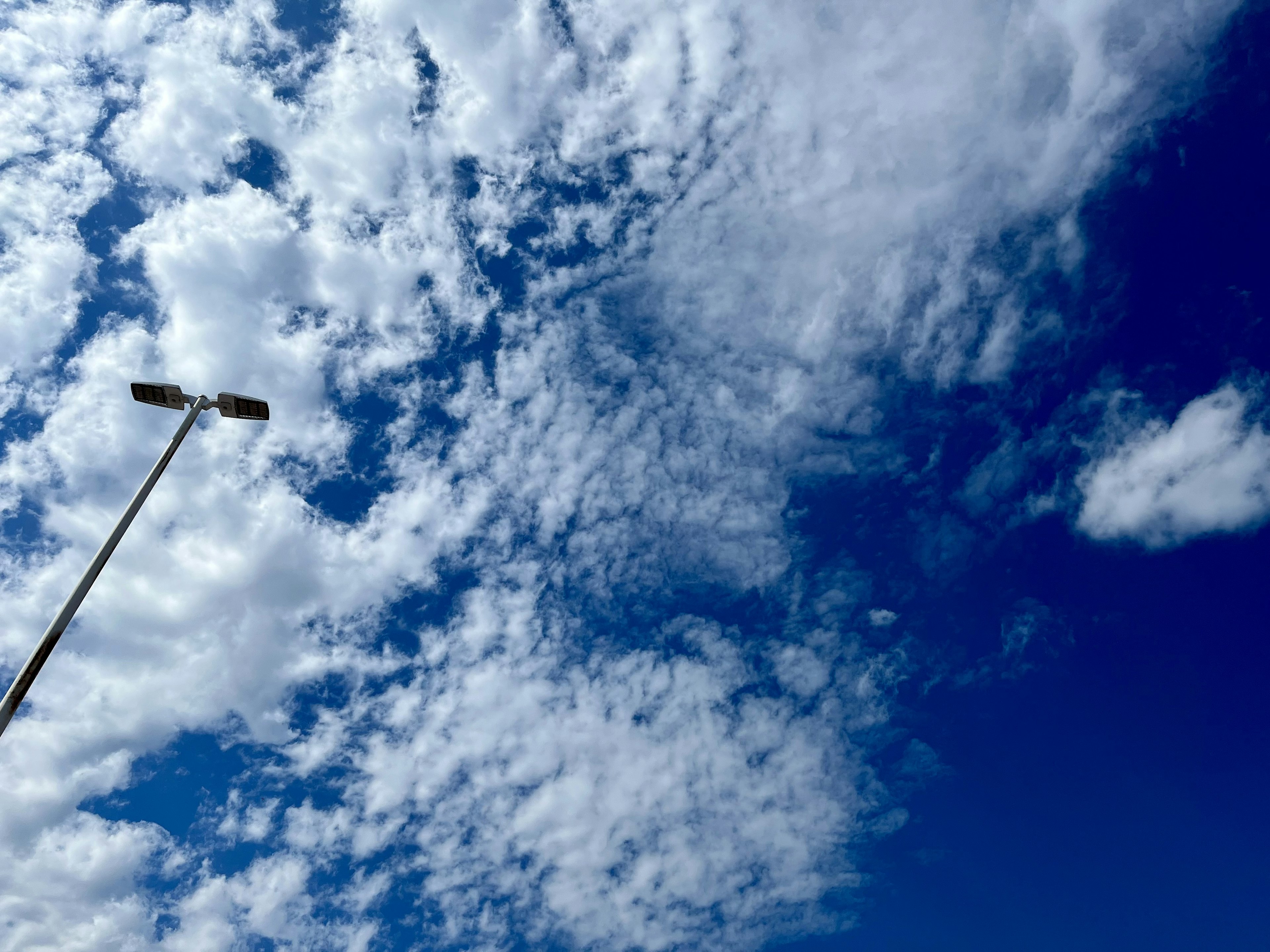 Clear blue sky with white clouds and a streetlight