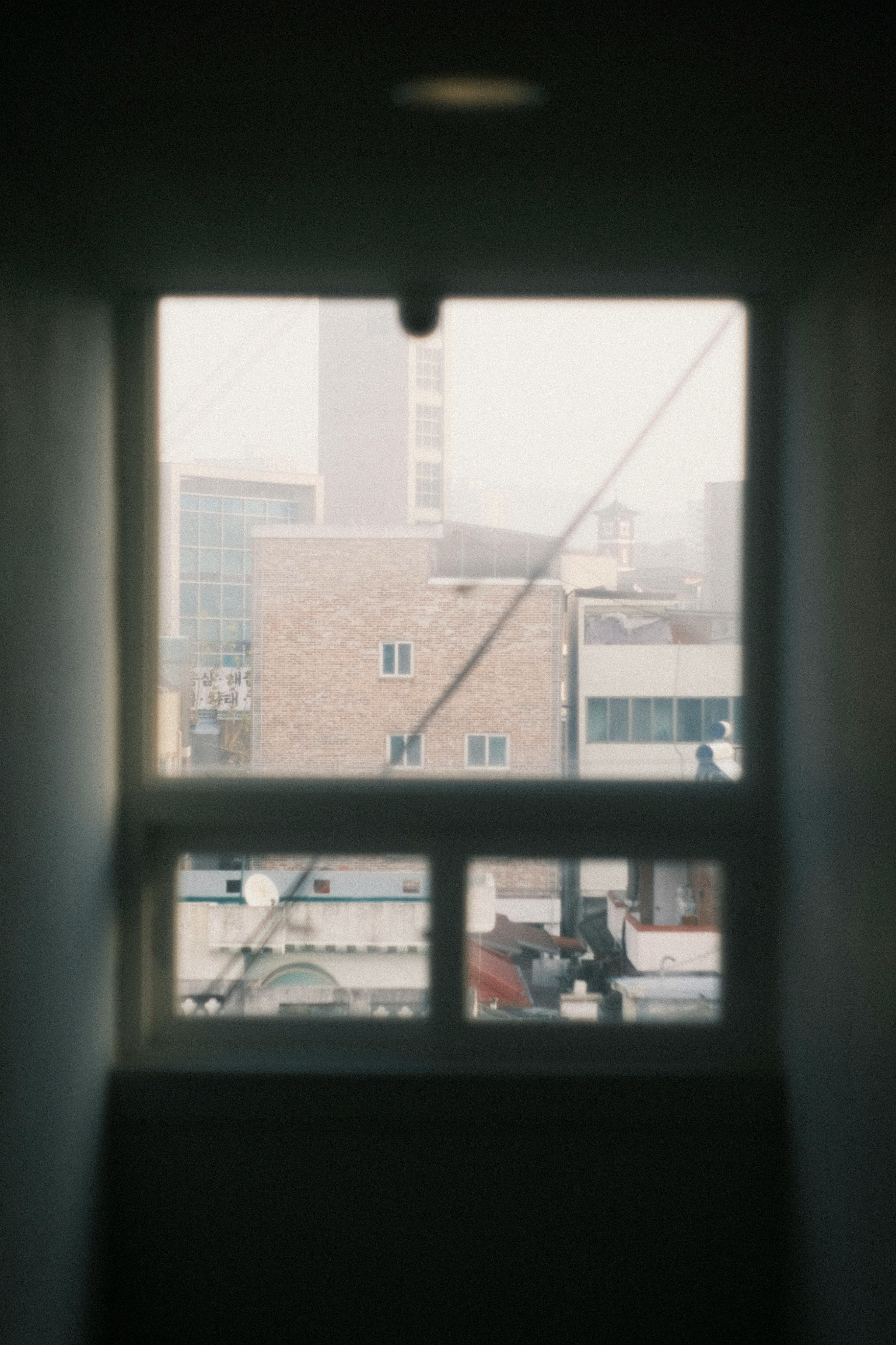 View of urban landscape through a window with buildings and a cloudy sky