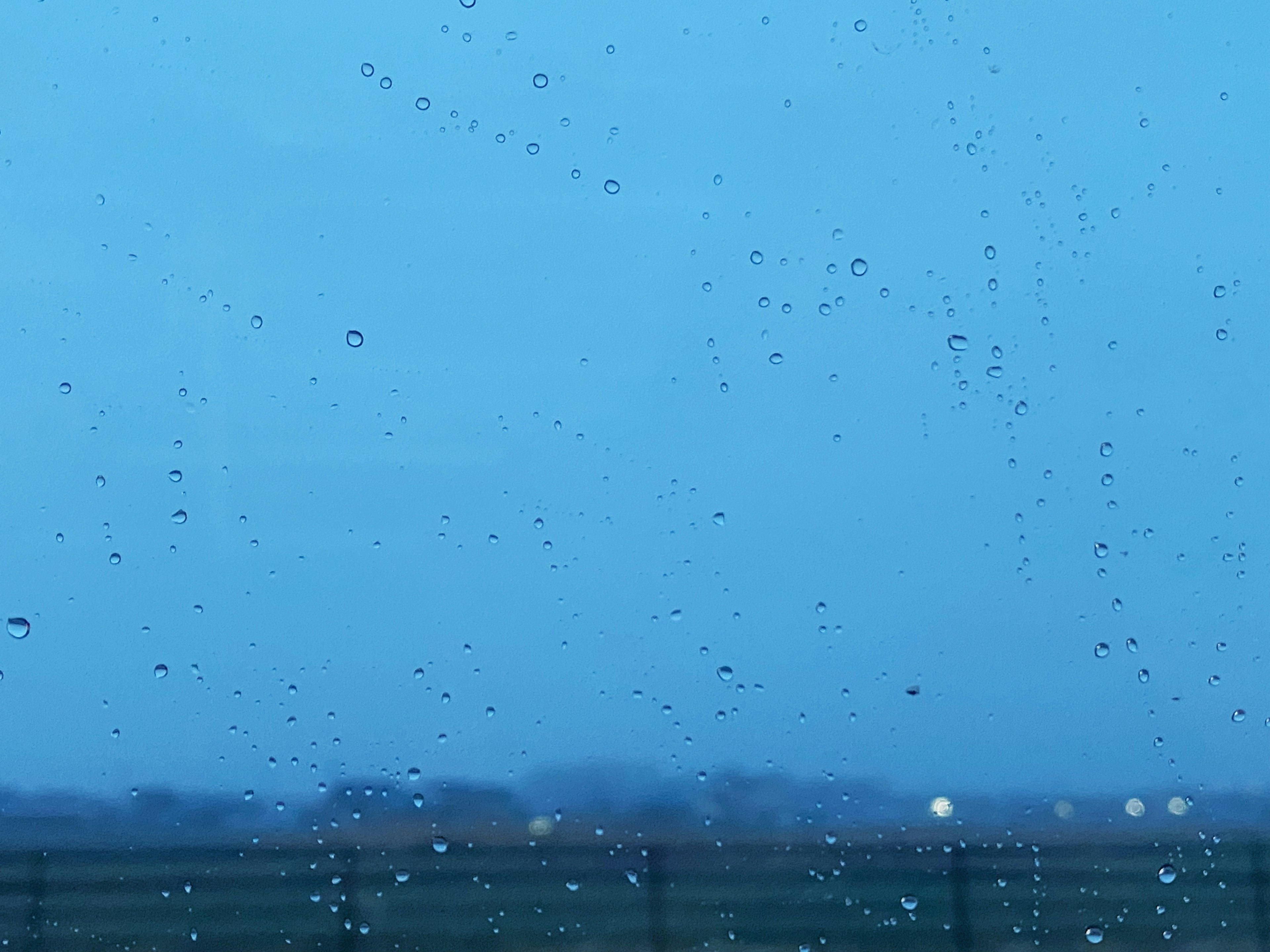 青い空の背景に雨滴がついた窓の外の風景