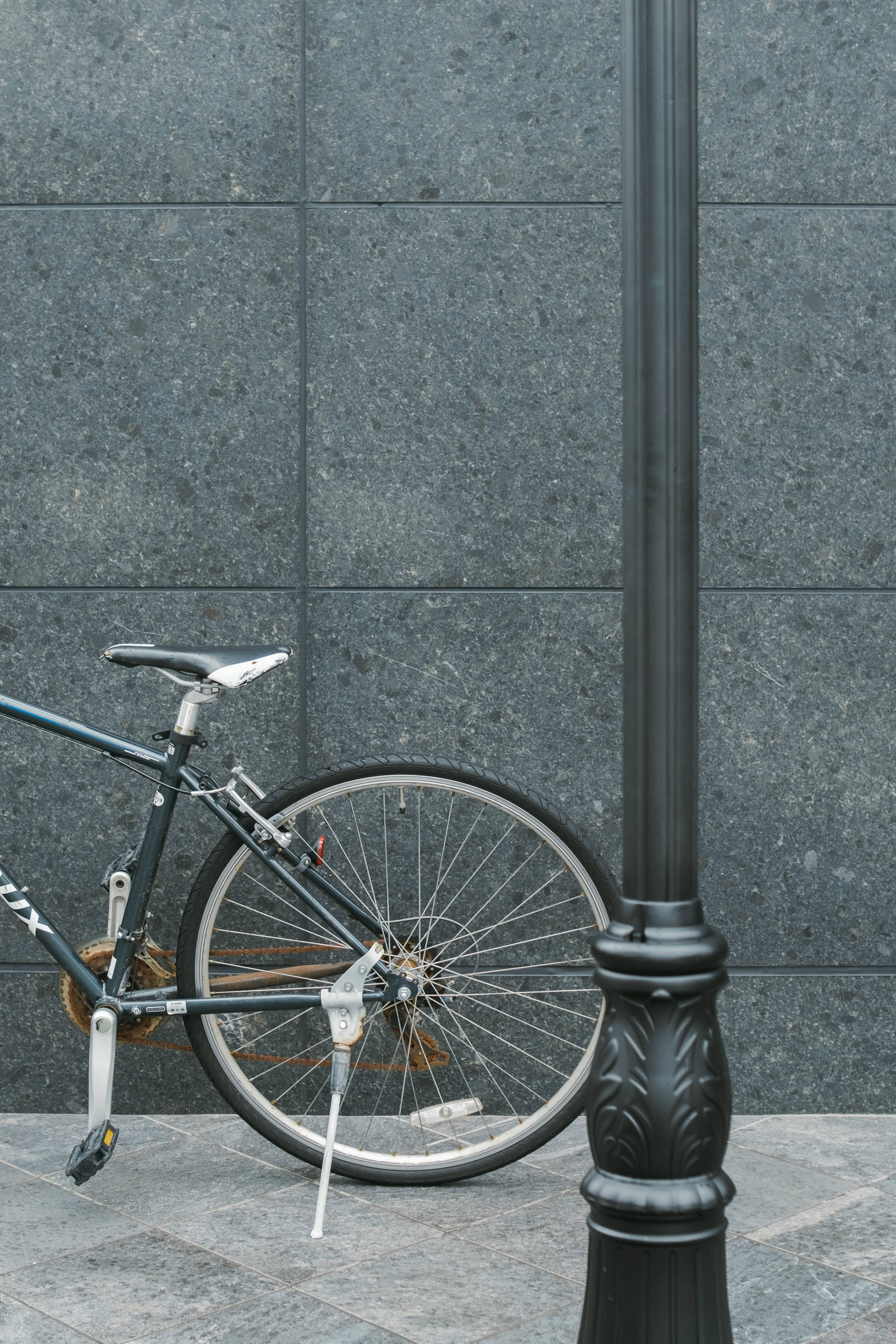 Bicicleta apoyada contra una pared negra con una farola