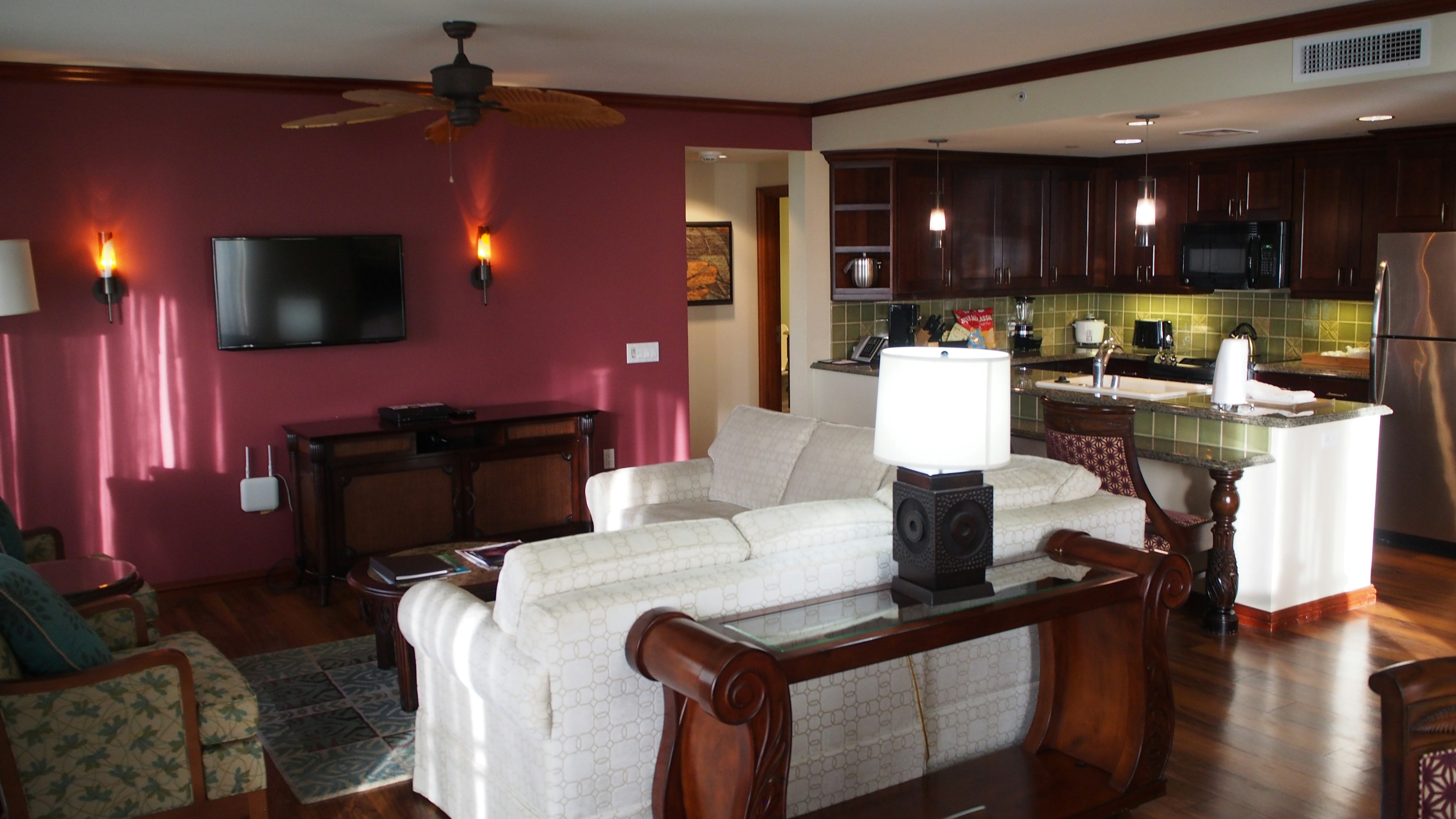 Modern living room and kitchen interior featuring a white sofa and wooden furniture Warm-toned walls and green tiles in the kitchen