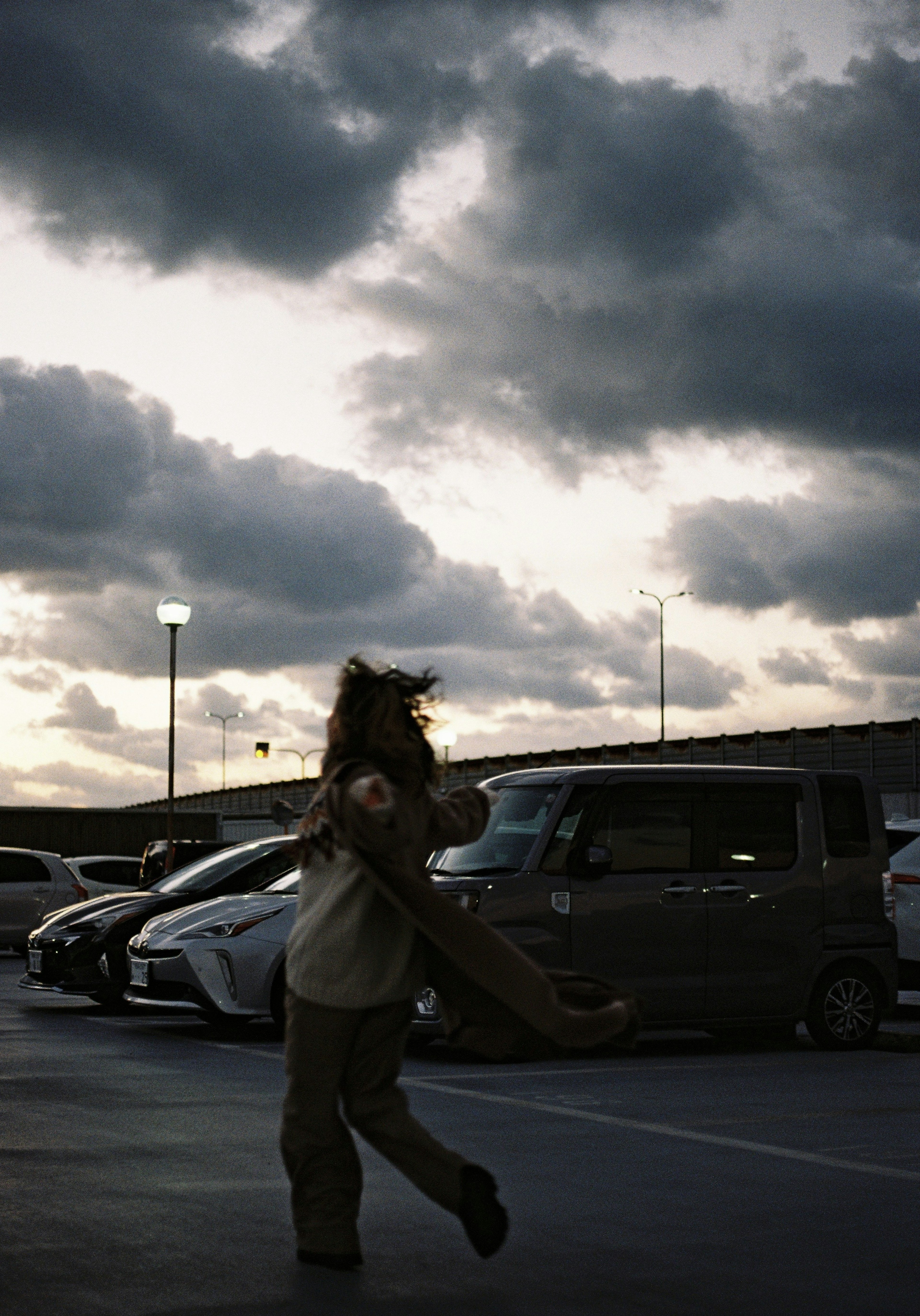 Femme dansant dans un parking sous un ciel nuageux