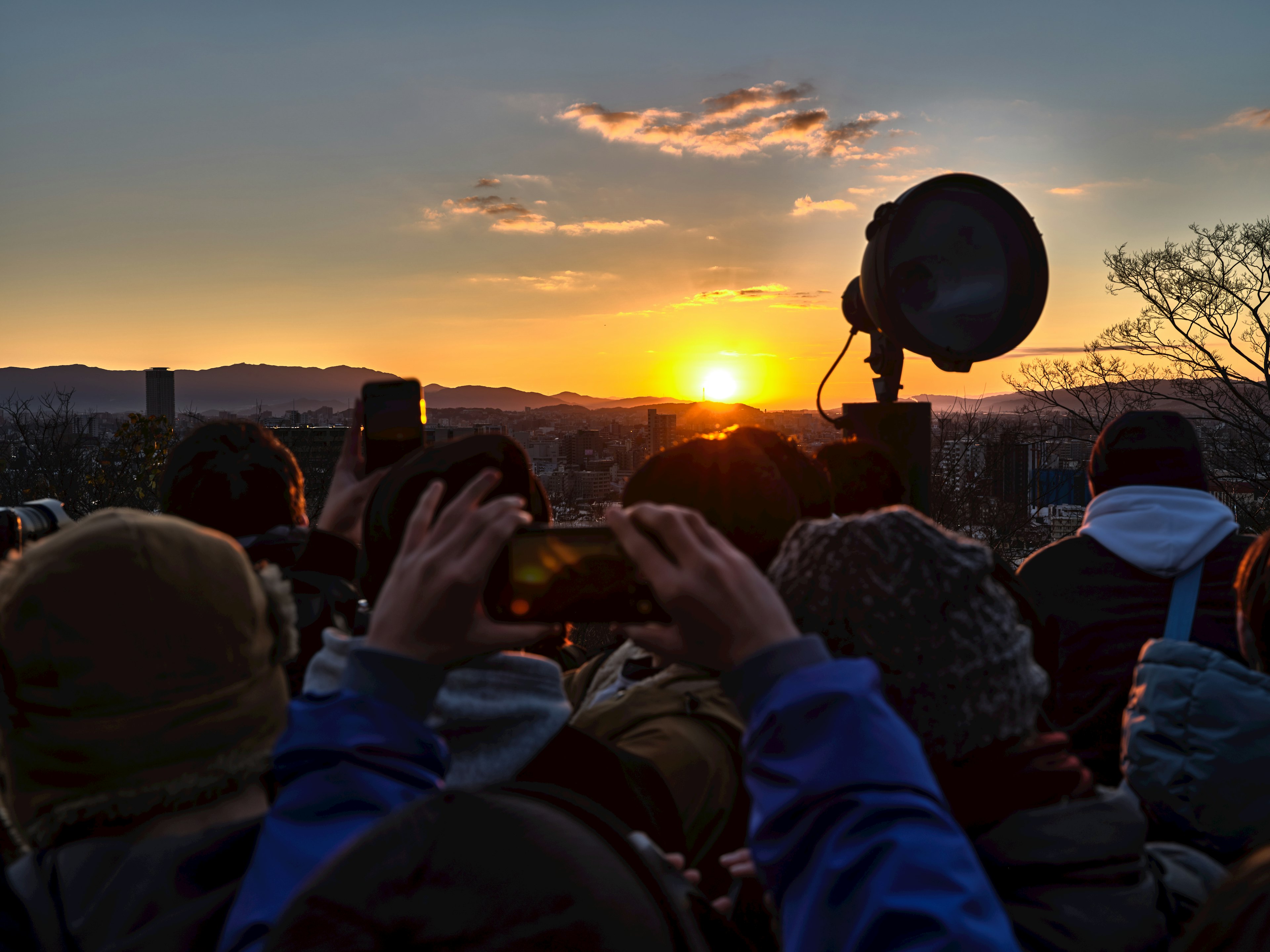 Folla che osserva l'alba con smartphone alzati per foto