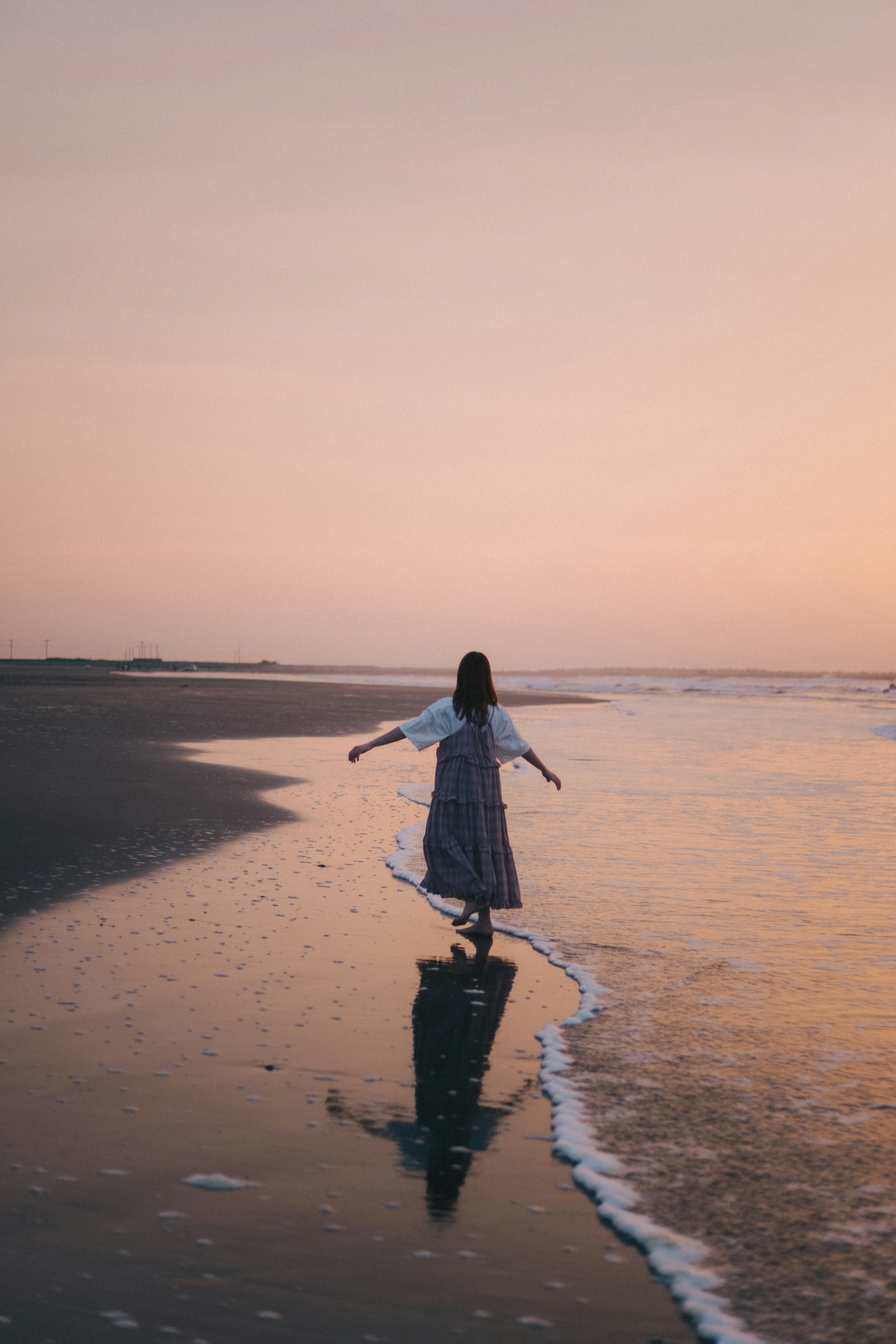 夕阳下海边走路的女性剪影