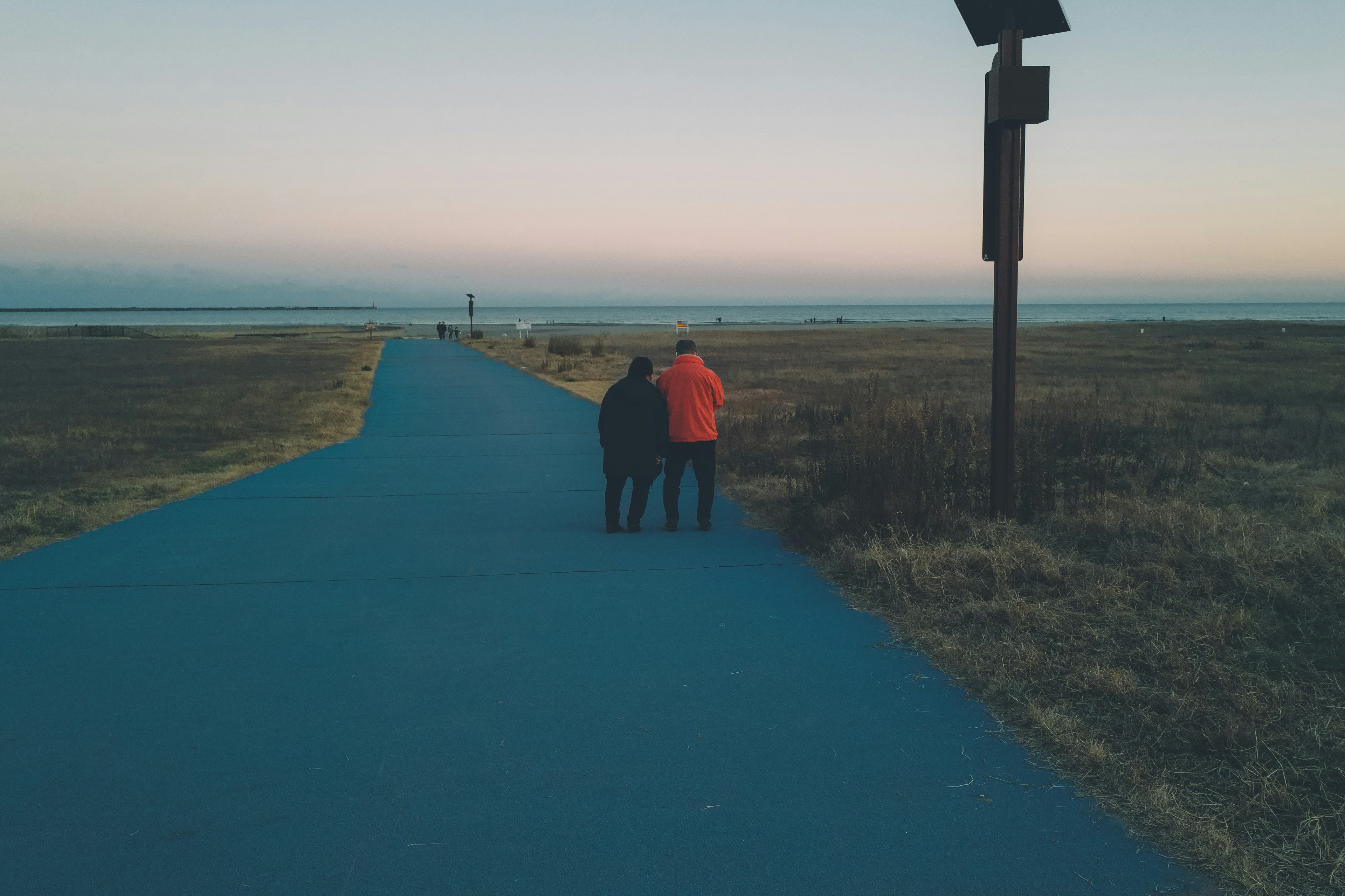 Deux personnes marchant sur un chemin au coucher du soleil avec un paysage naturel