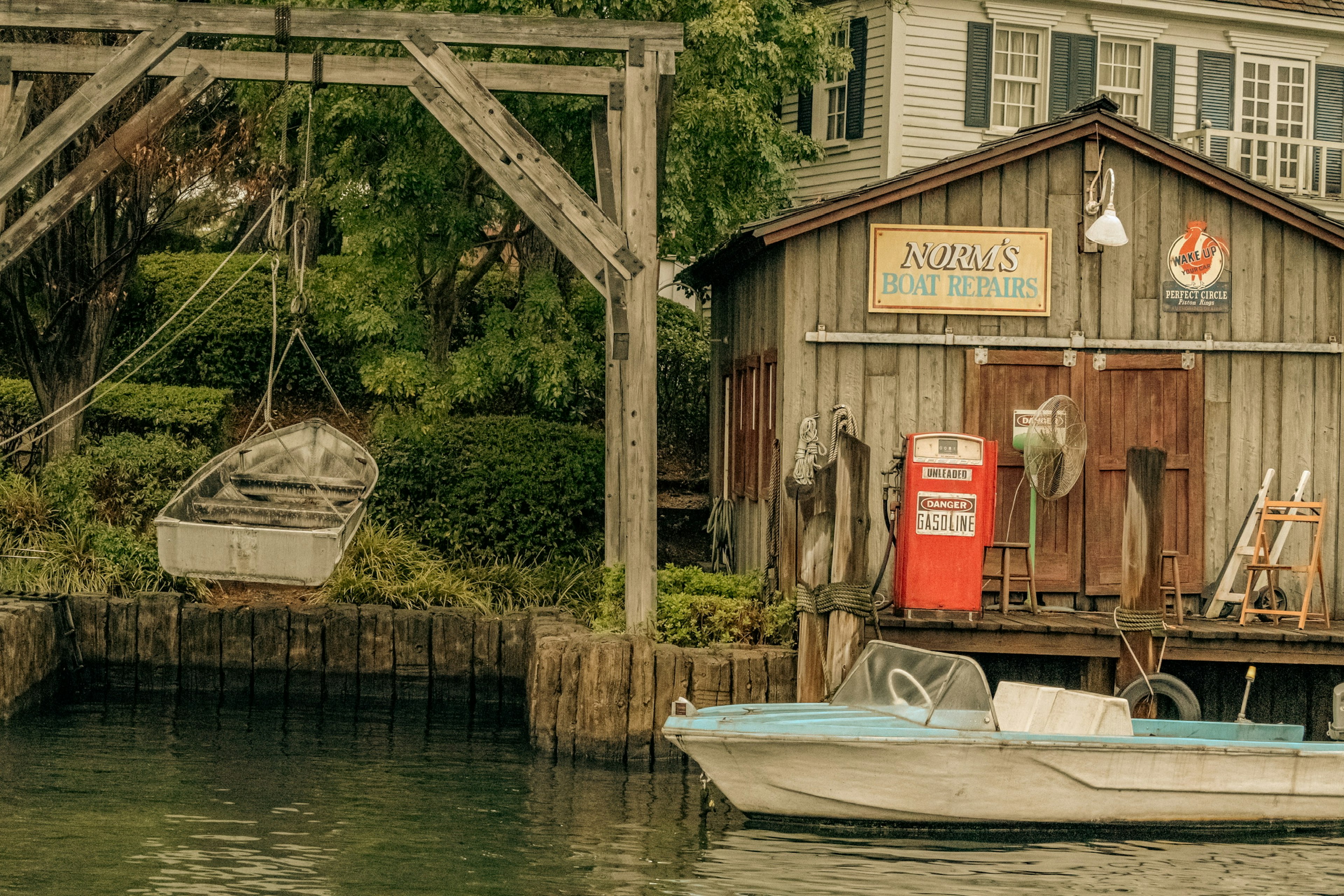 A quaint wooden shed near the water with boats and a vintage sign