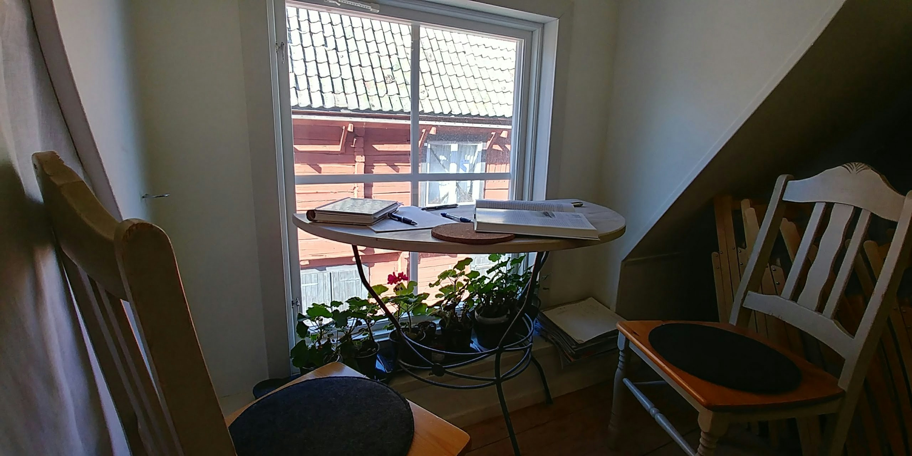 Chambre confortable avec une petite table et des chaises près de la fenêtre plantes placées sous la table