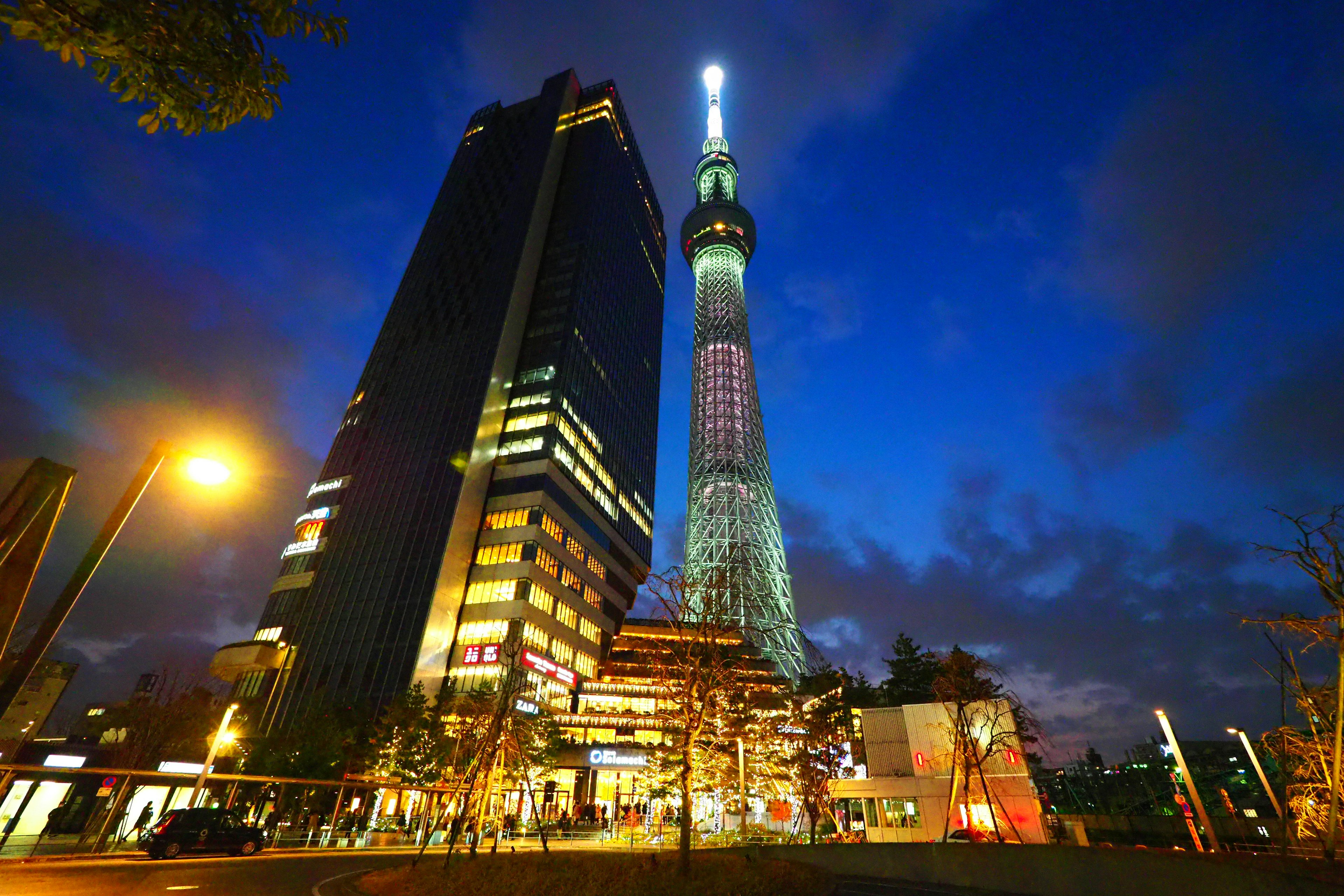 东京晴空塔在夜间照亮，附近建筑与生动的天空相映成趣