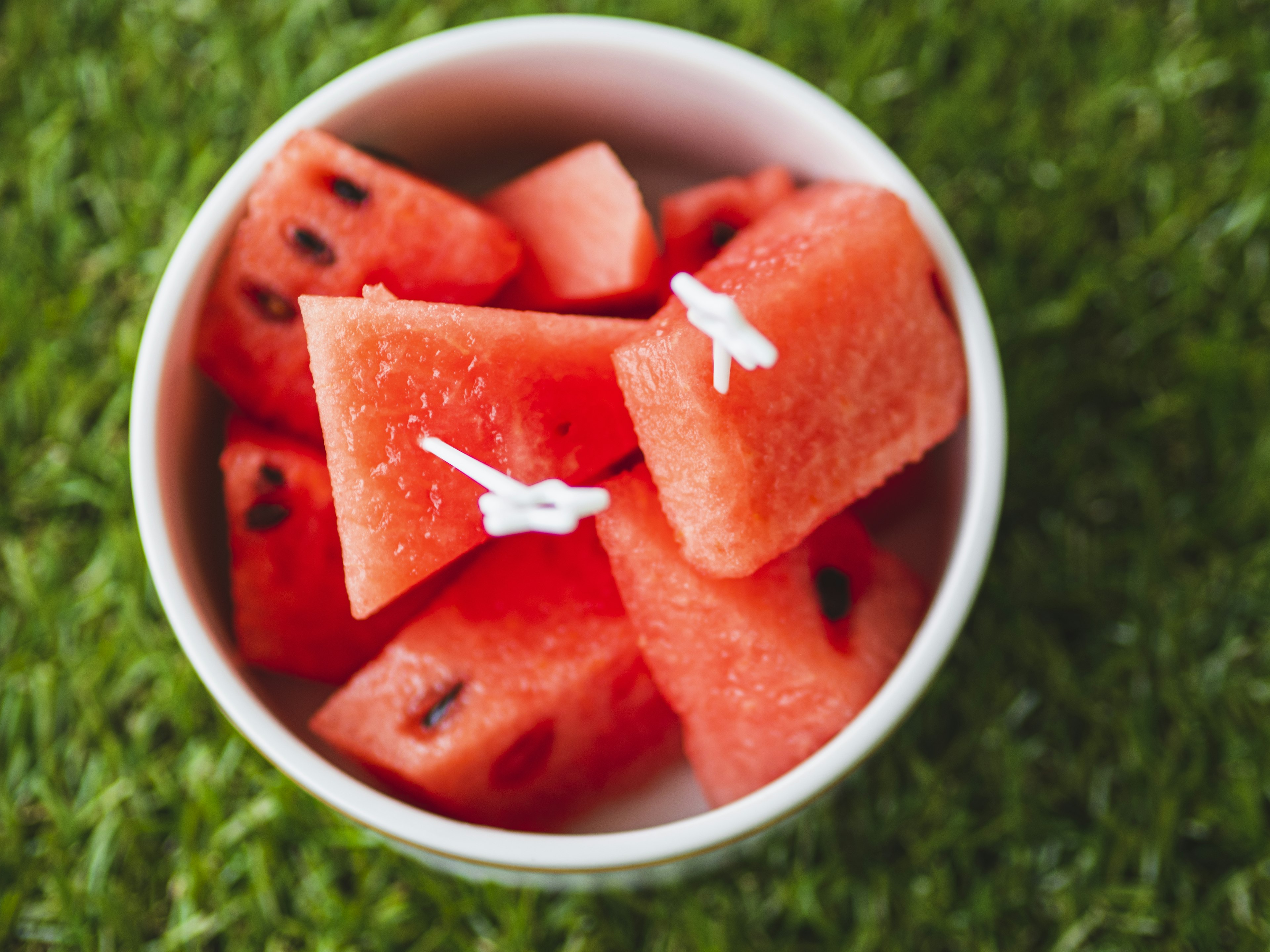 Frische Wassermelonenwürfel in einer weißen Tasse auf grünem Gras