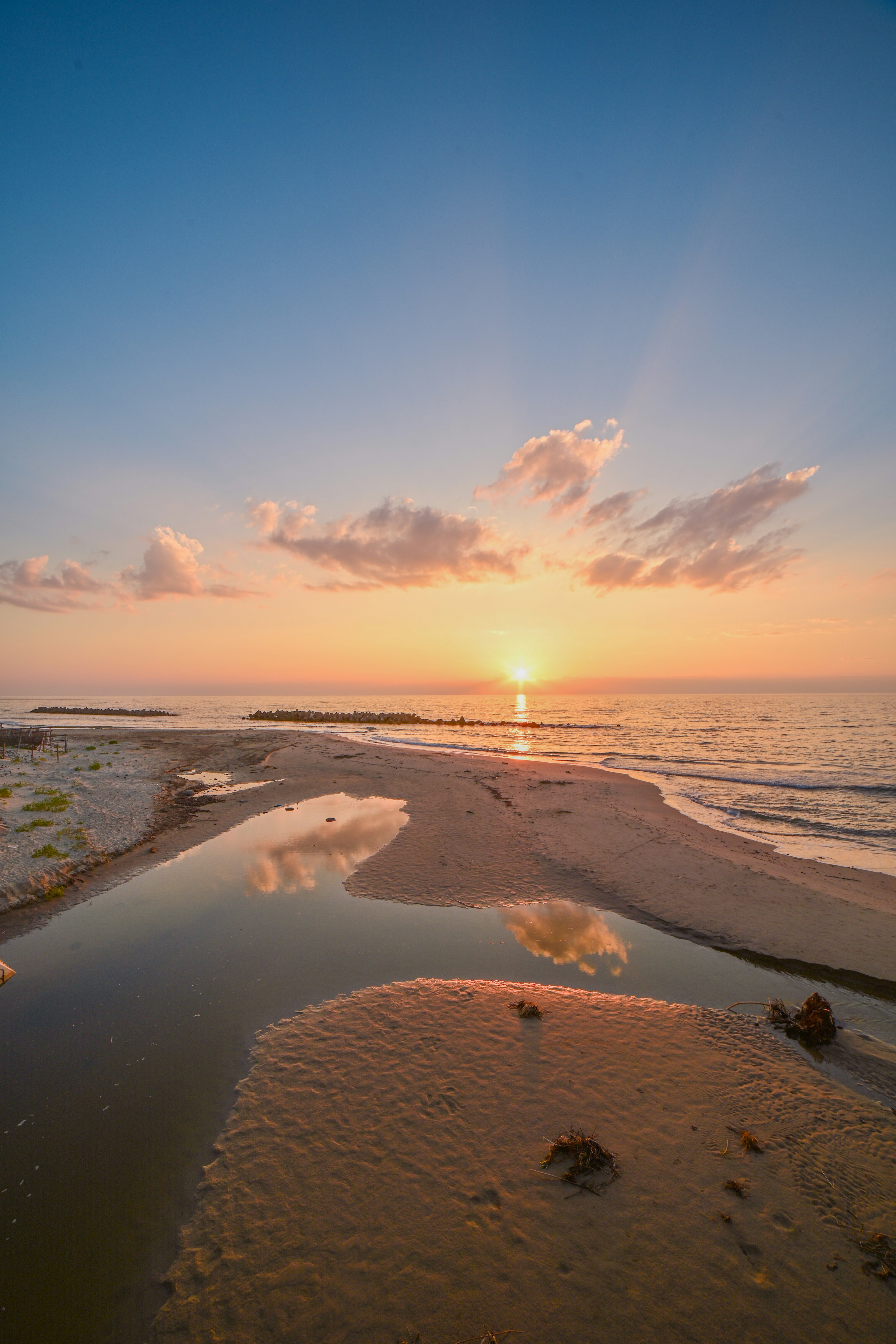 美しい夕日が海に沈む様子を捉えた海岸の風景 干潟と水たまりが反射を生む