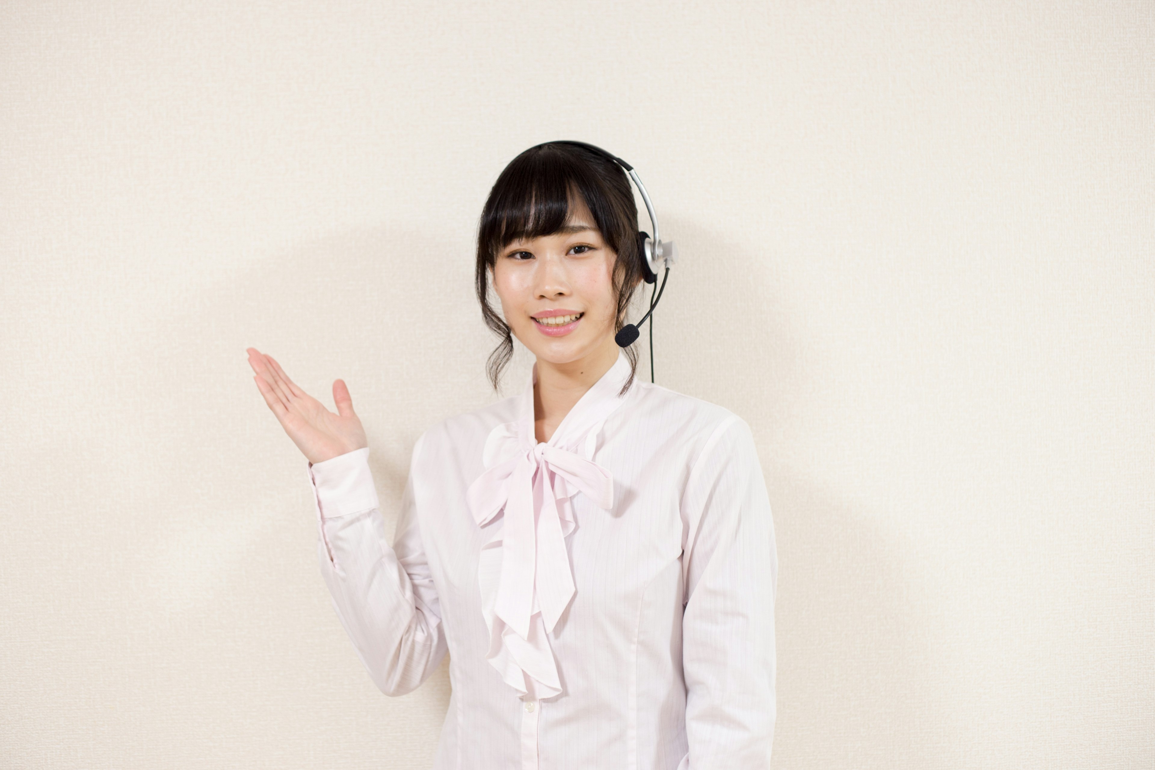 Une femme en chemise blanche portant un casque souriant et levant la main