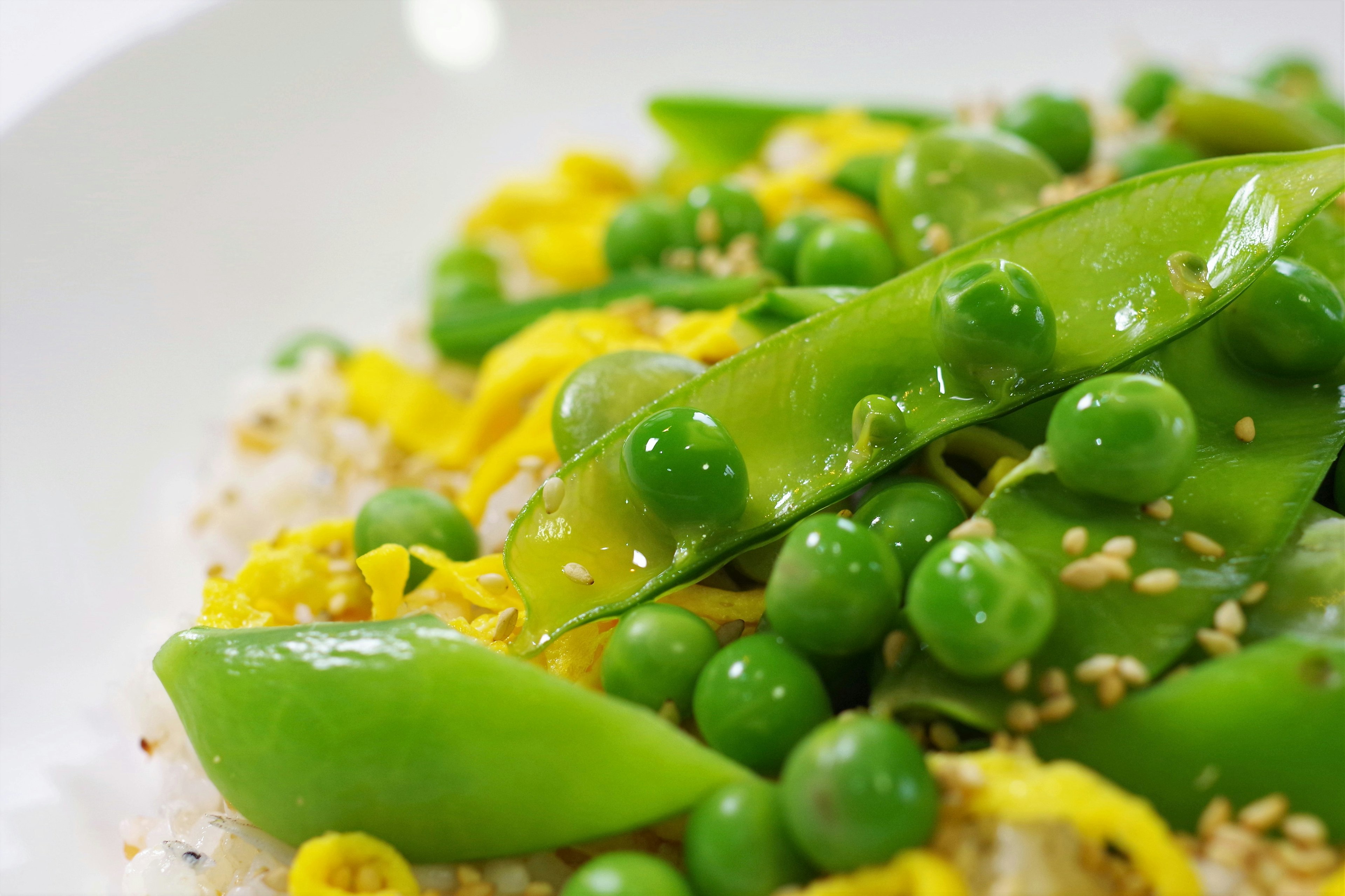 Plat de pois mange-tout et de petits pois verts servi dans une assiette blanche