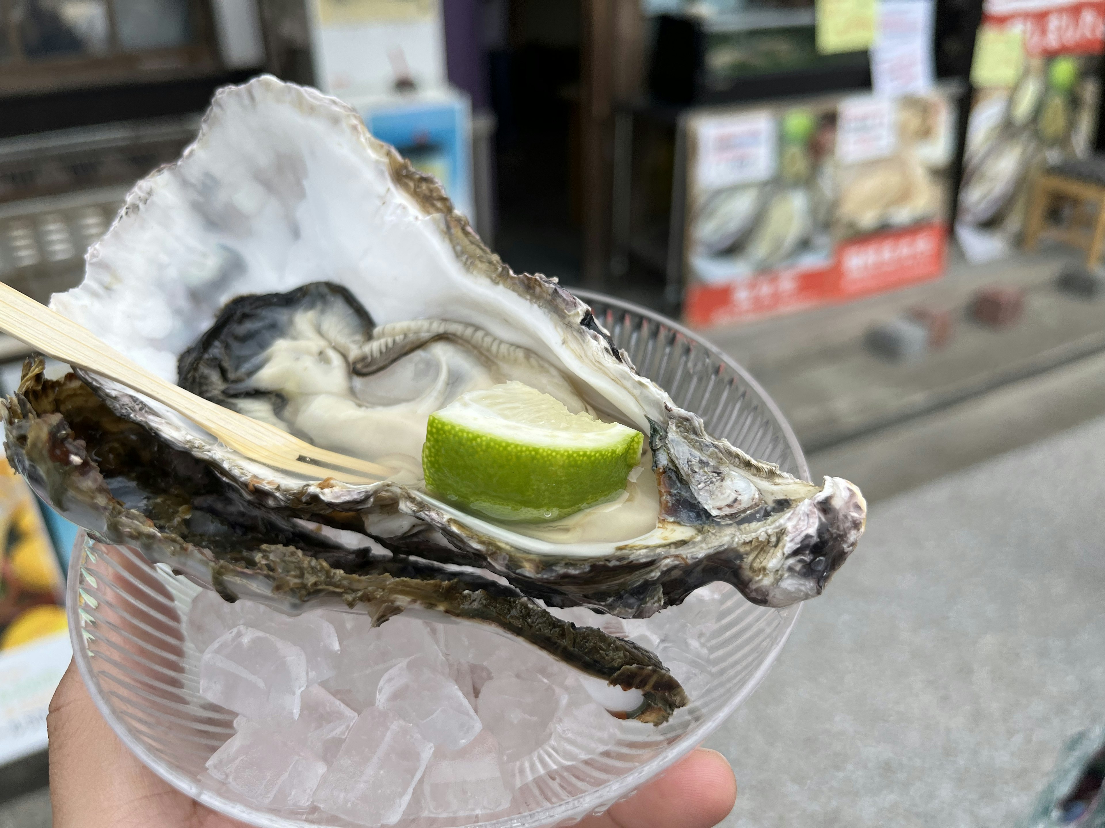 Ostra fresca con una rodaja de lima en una taza transparente