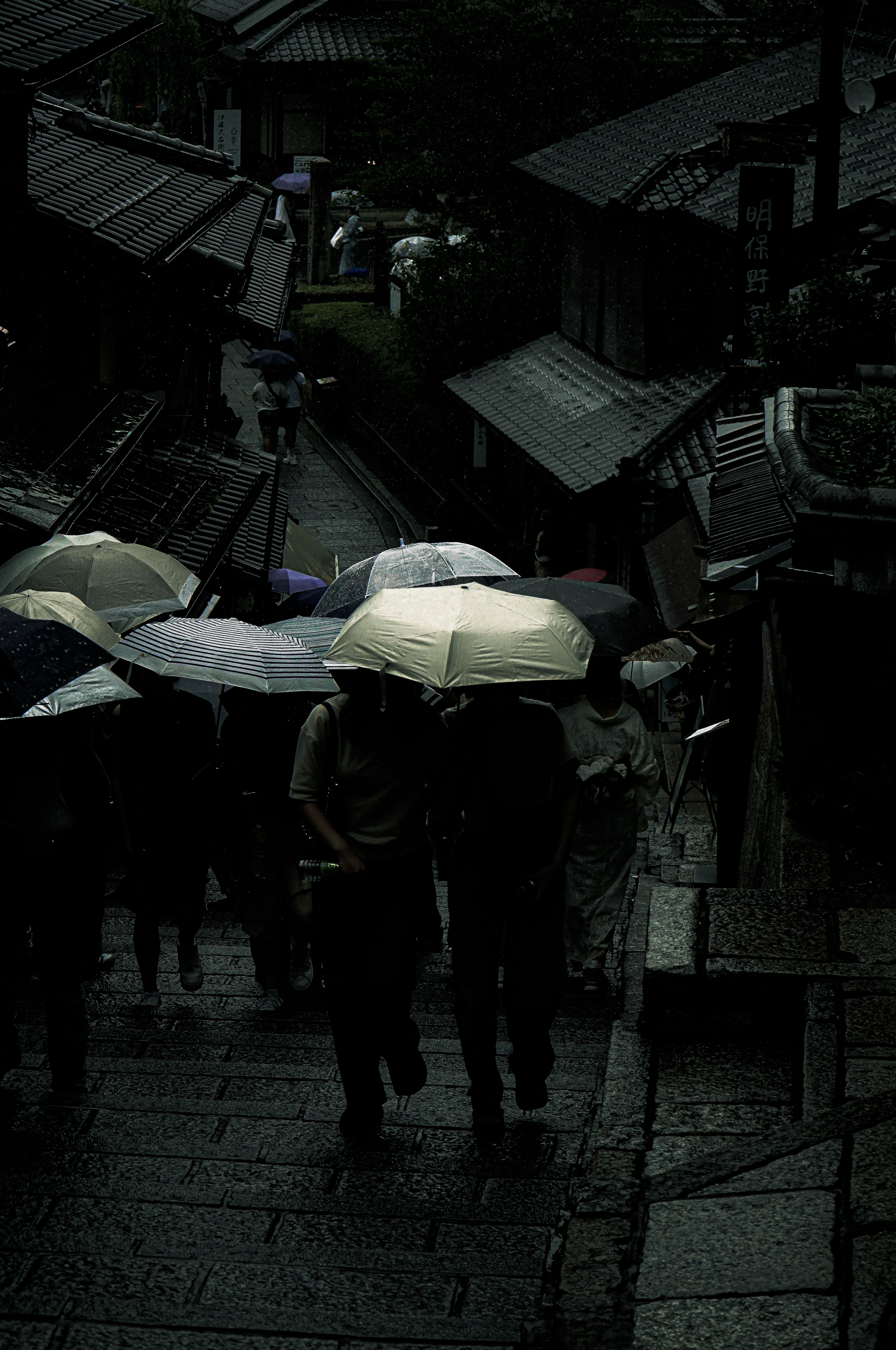 雨の中を歩く人々と傘がある古い街並み