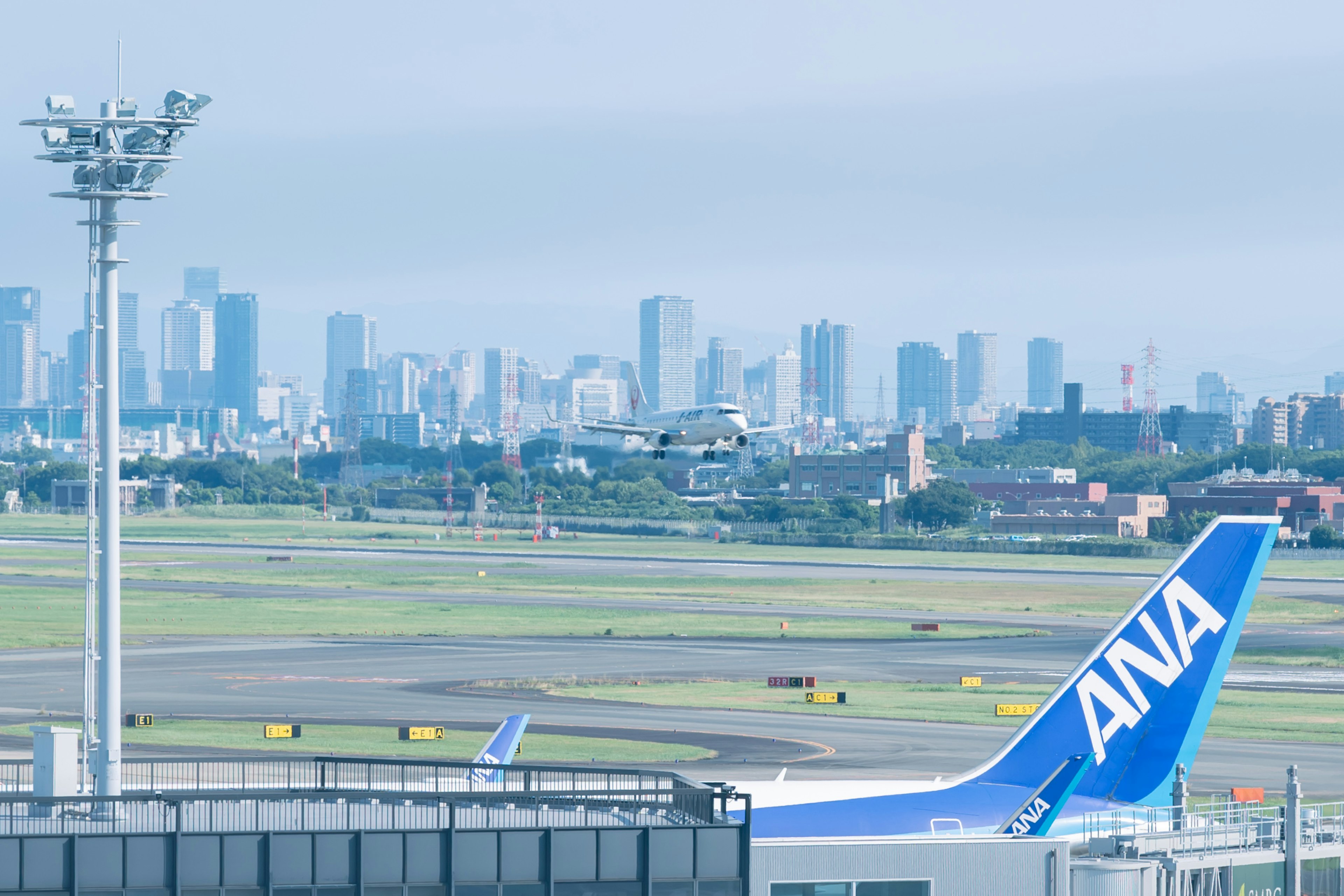 Avión de ANA en el aeropuerto con el horizonte de la ciudad de fondo