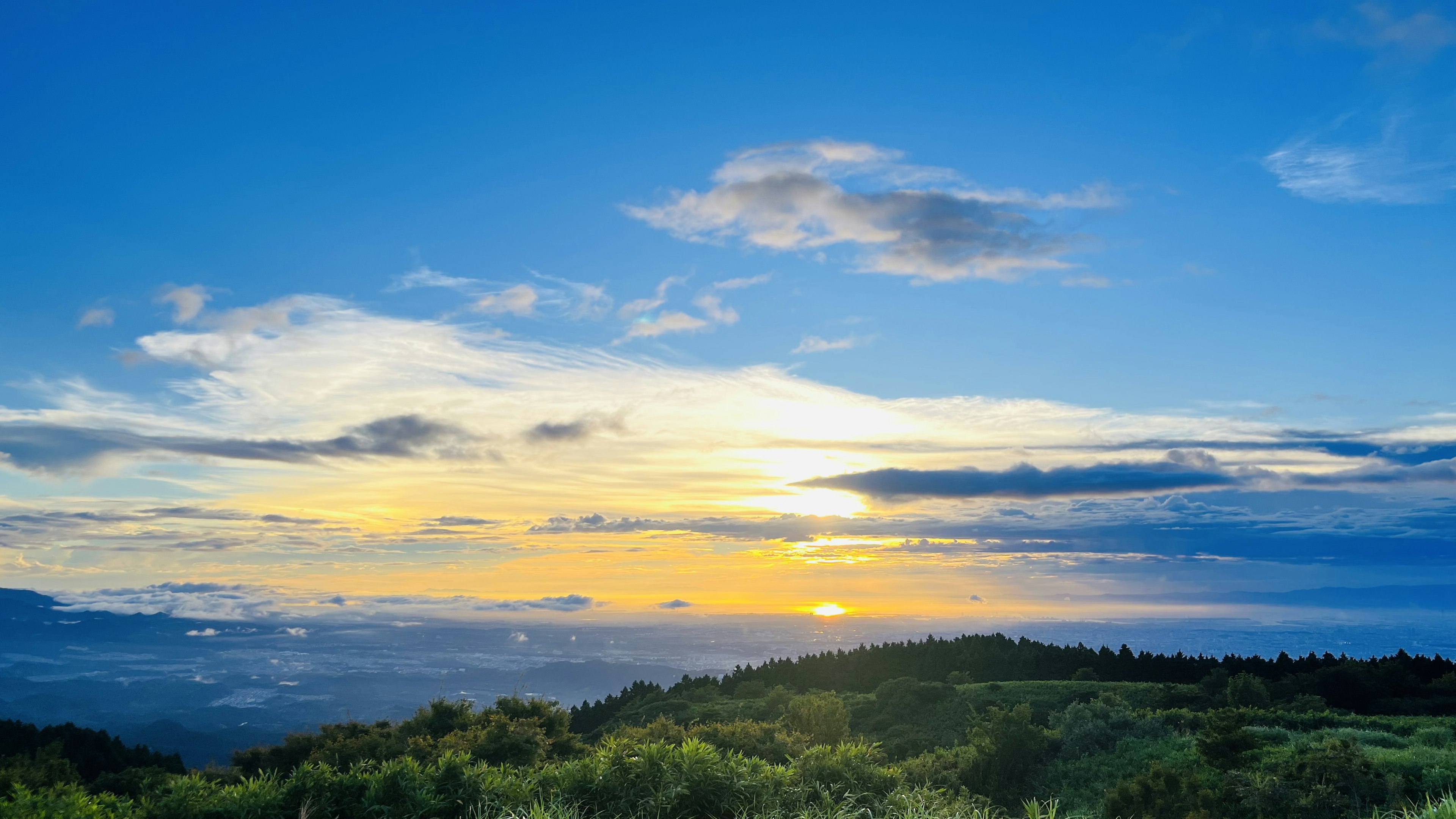 Pemandangan indah dengan matahari terbenam di bawah langit biru dan awan