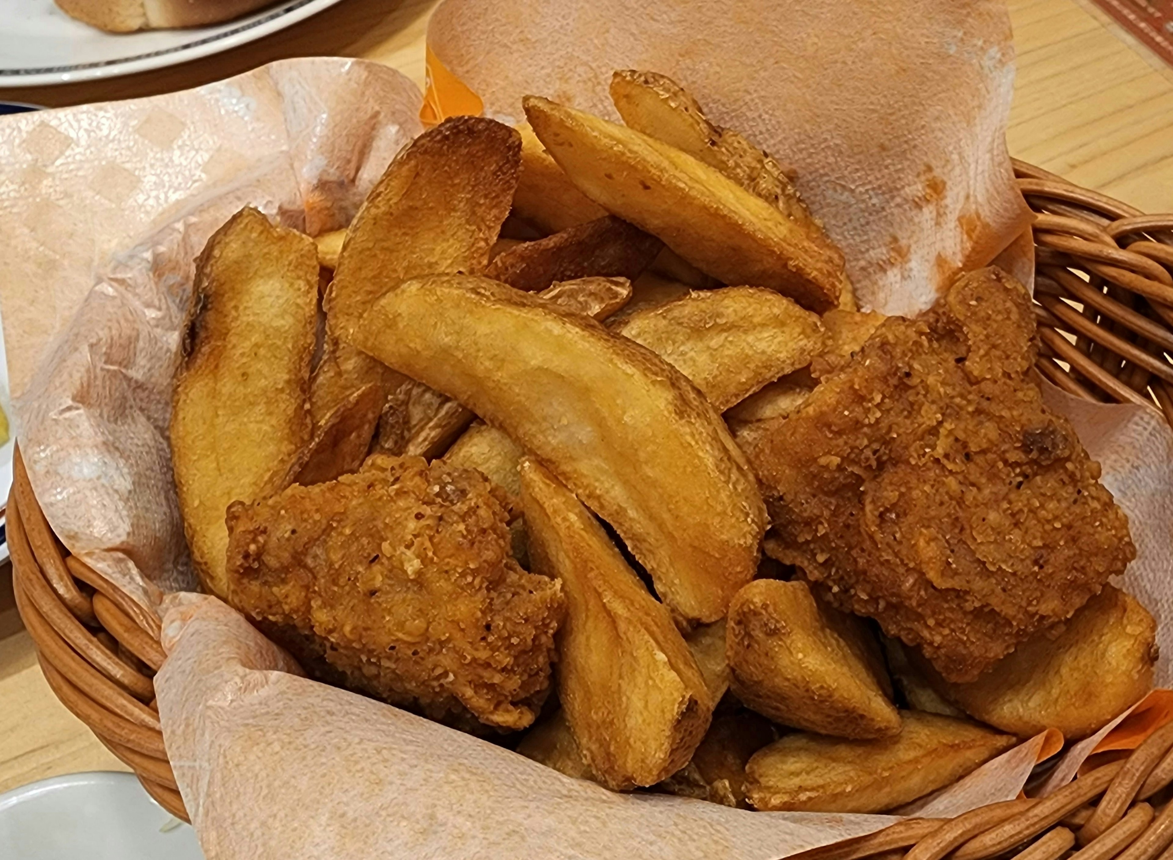 Cesto pieno di pollo fritto e spicchi di patate