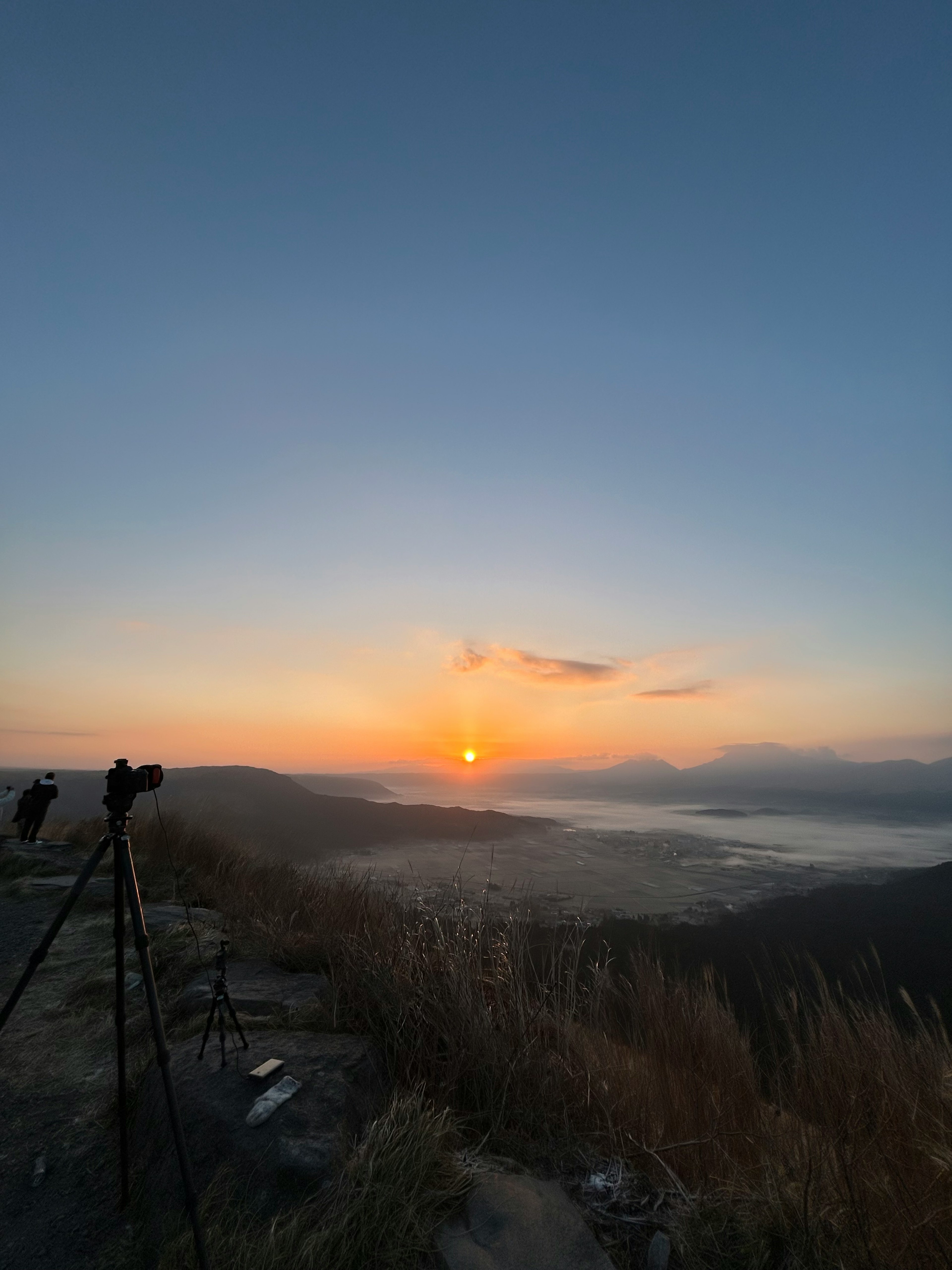 夕日が沈む山の景色と三脚が見える