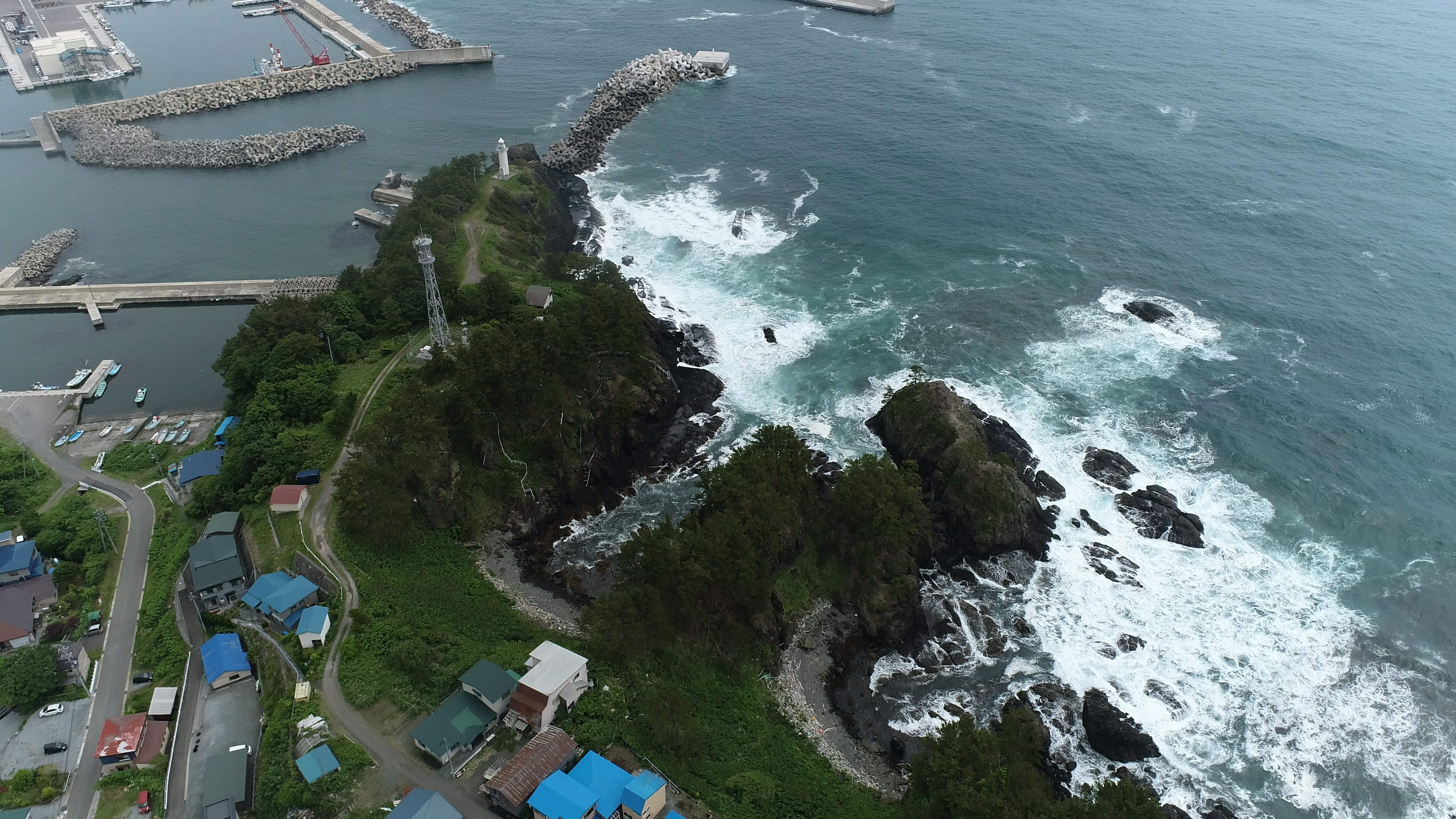 Luftaufnahme einer Küste mit brechenden Wellen und Felsen