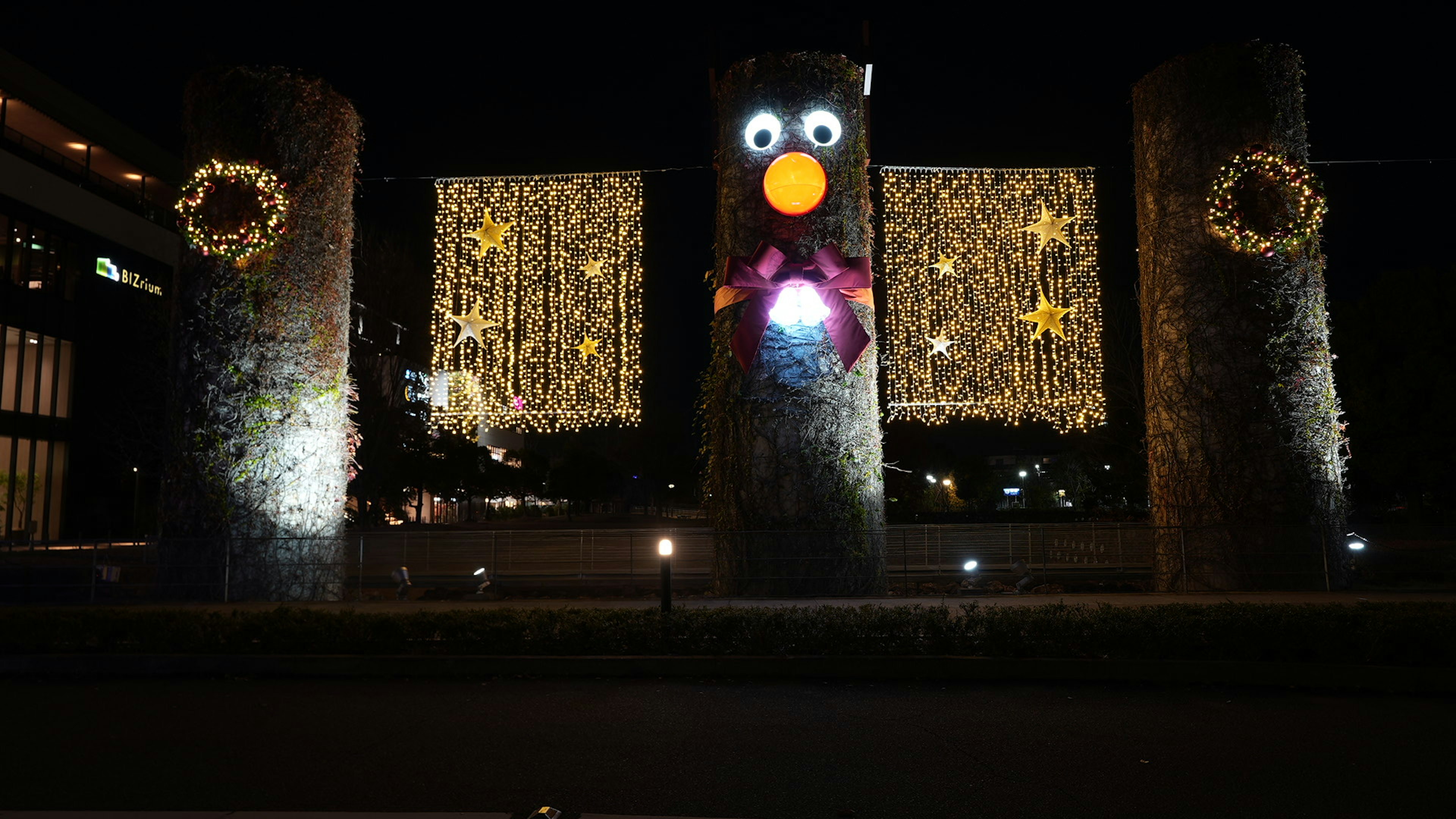 Weihnachtsdekoration mit beleuchteten Steinsäulen und Kränzen bei Nacht