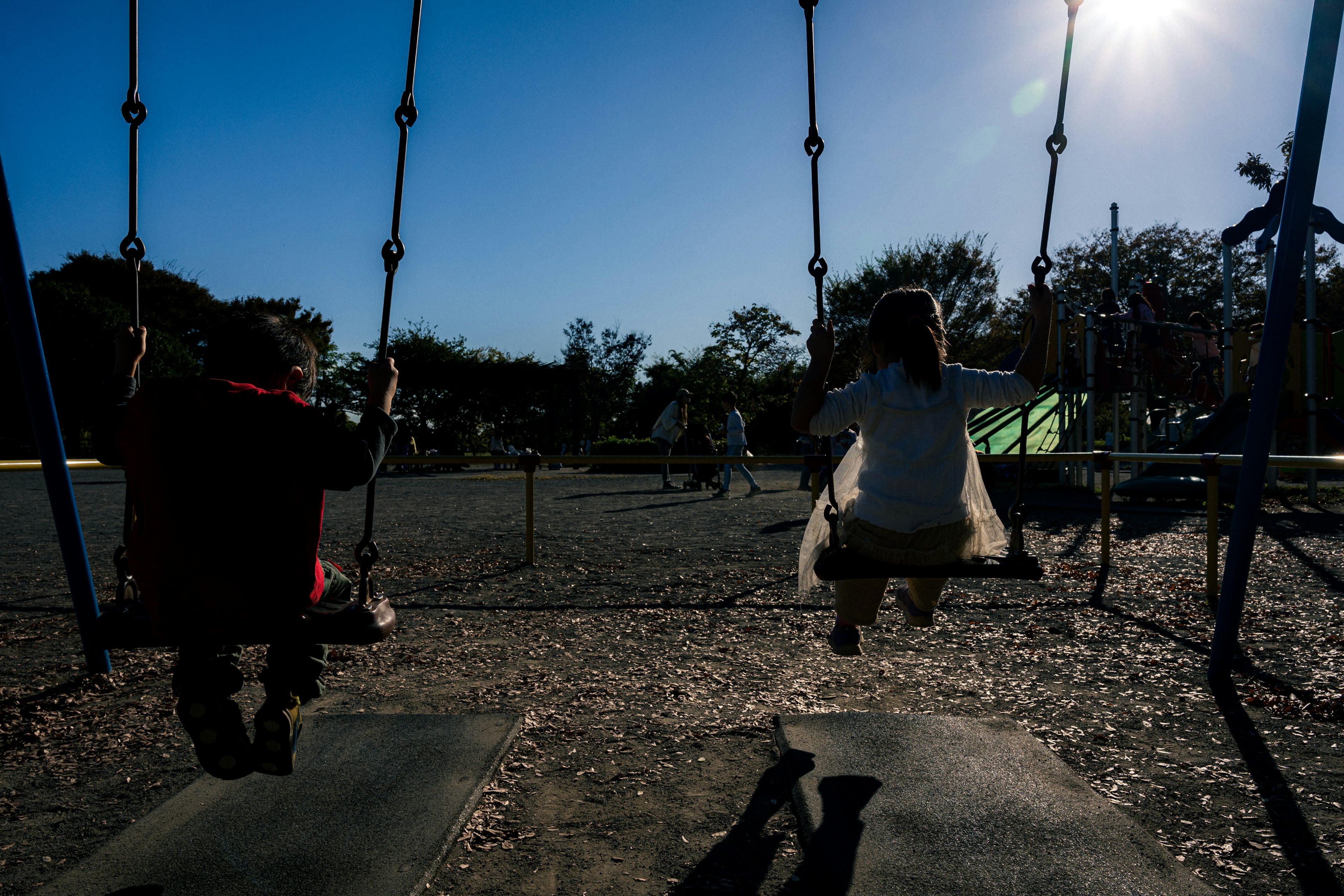 Zwei Kinder spielen auf Schaukeln in einem Spielplatz