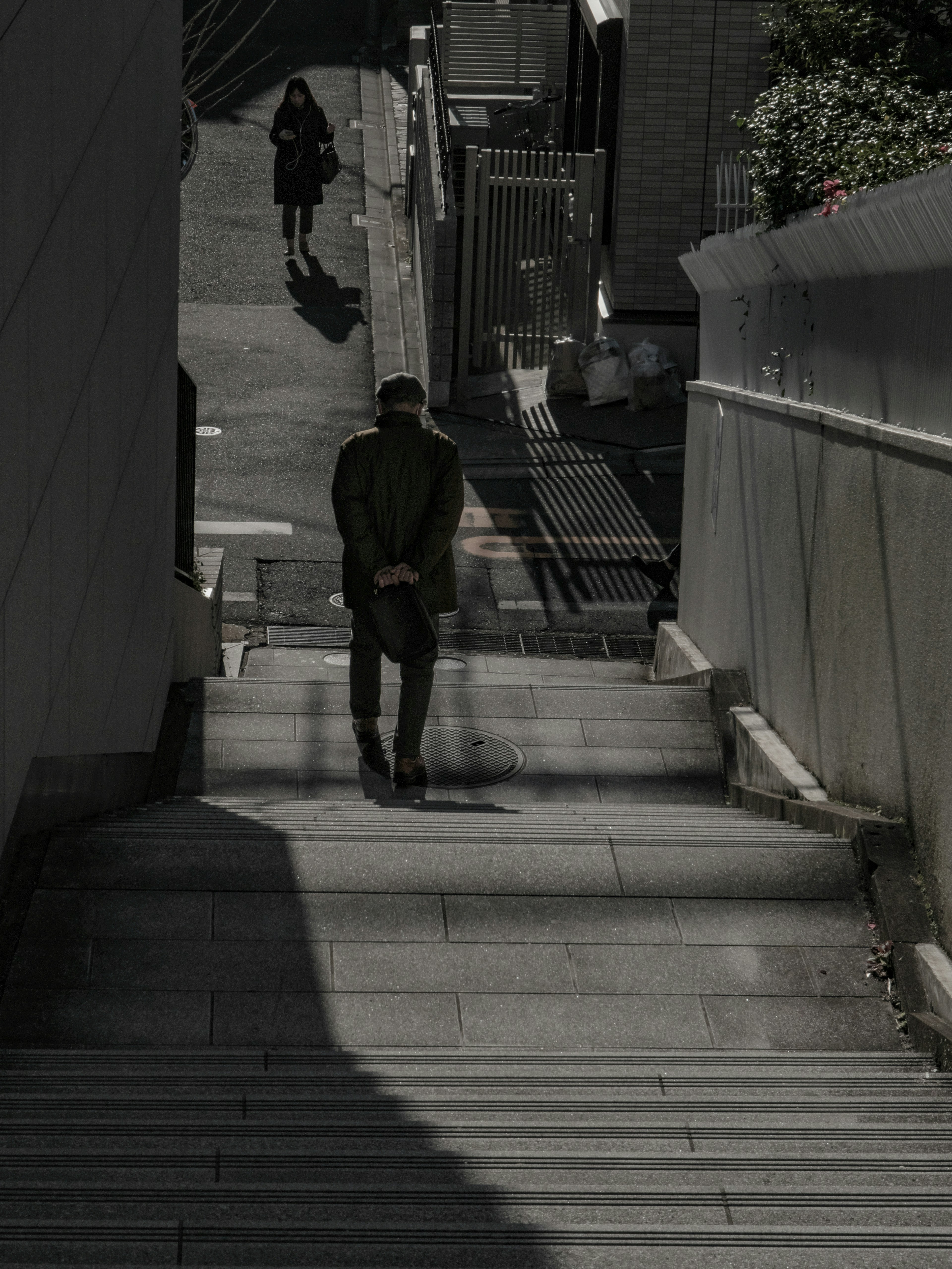 Silhouette of a person walking down stairs with another silhouette in the background