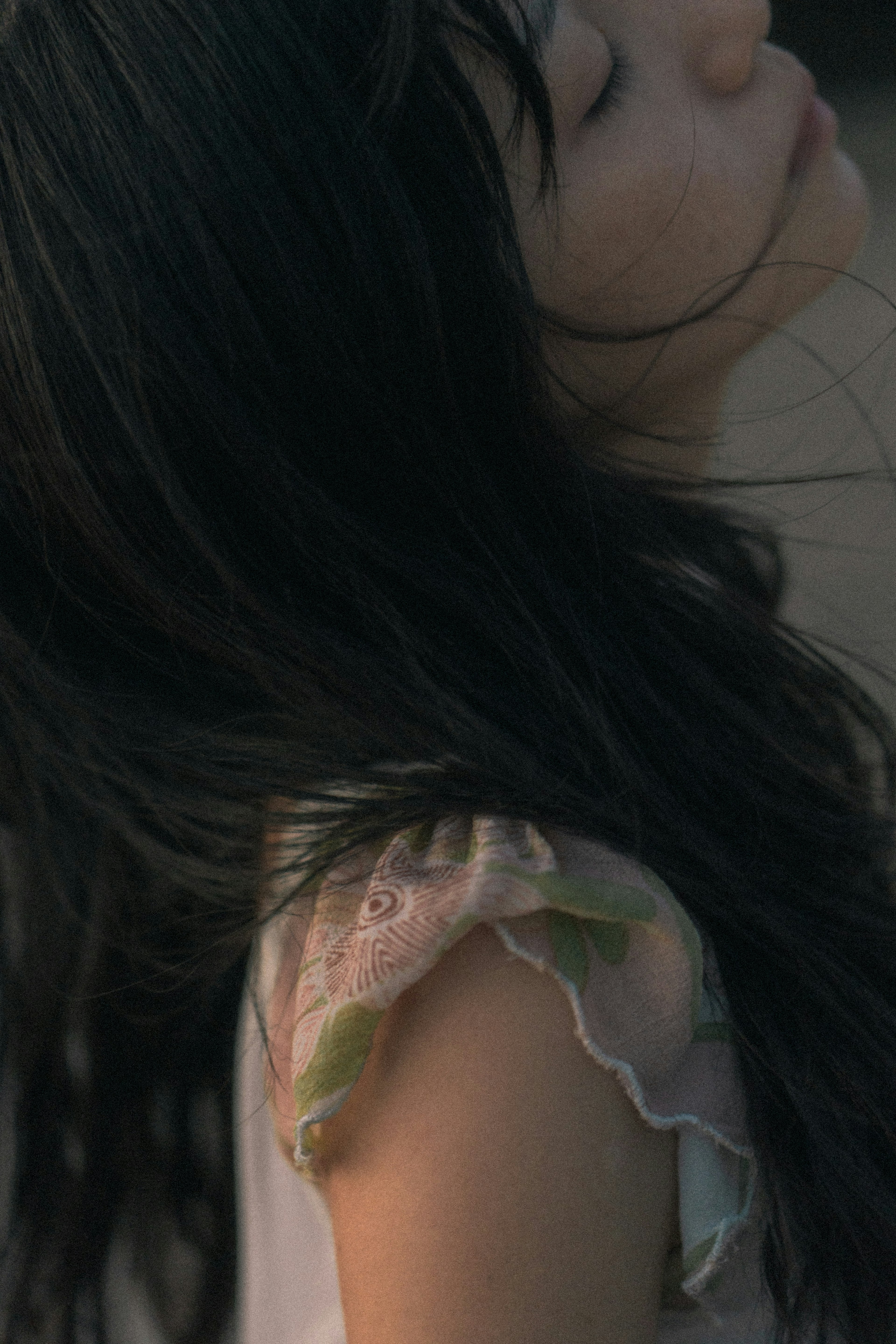 Una niña con cabello negro mira de lado su cabello fluye con el viento