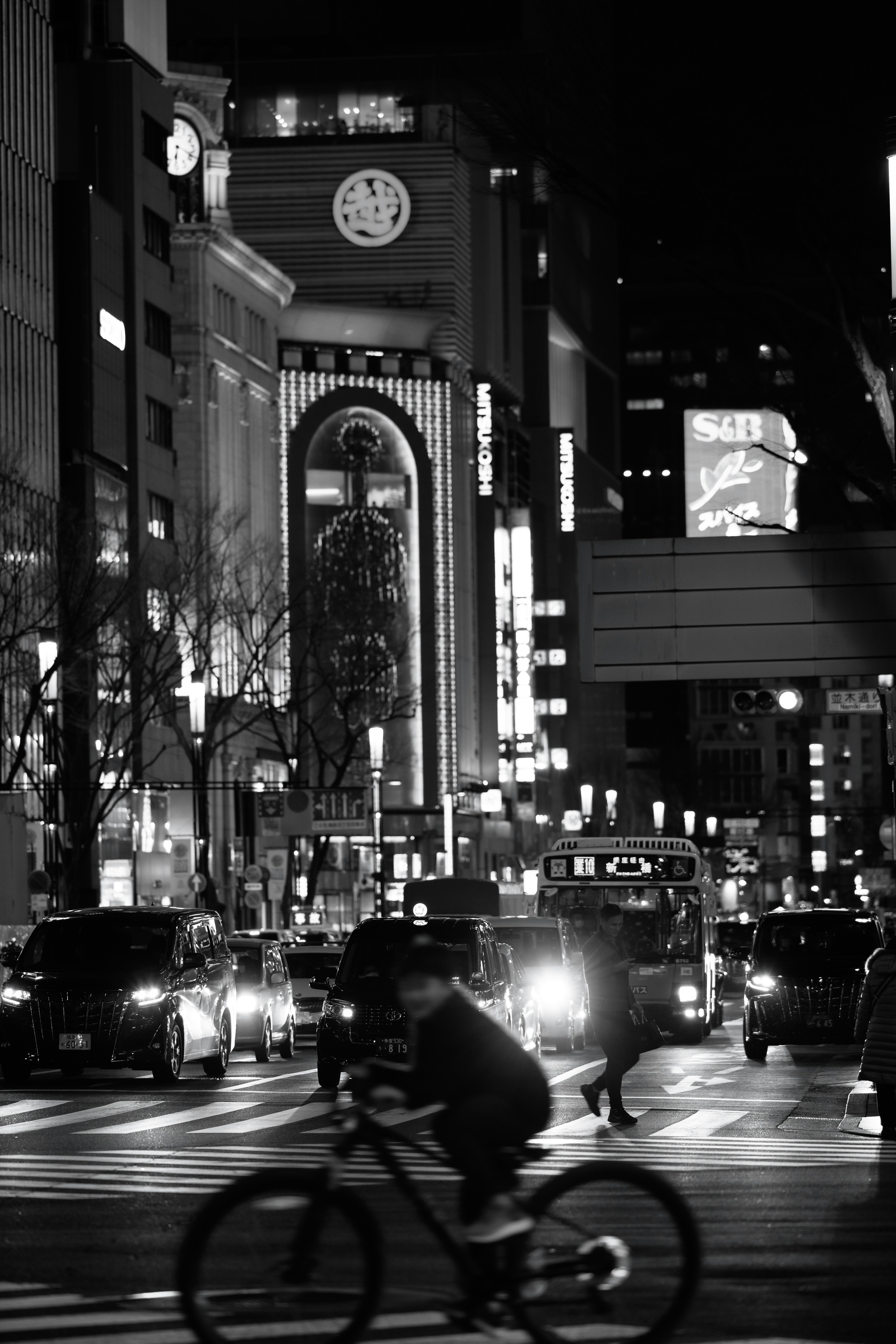 Paysage urbain nocturne avec un cycliste traversant l'intersection bâtiment avec horloge en arrière-plan