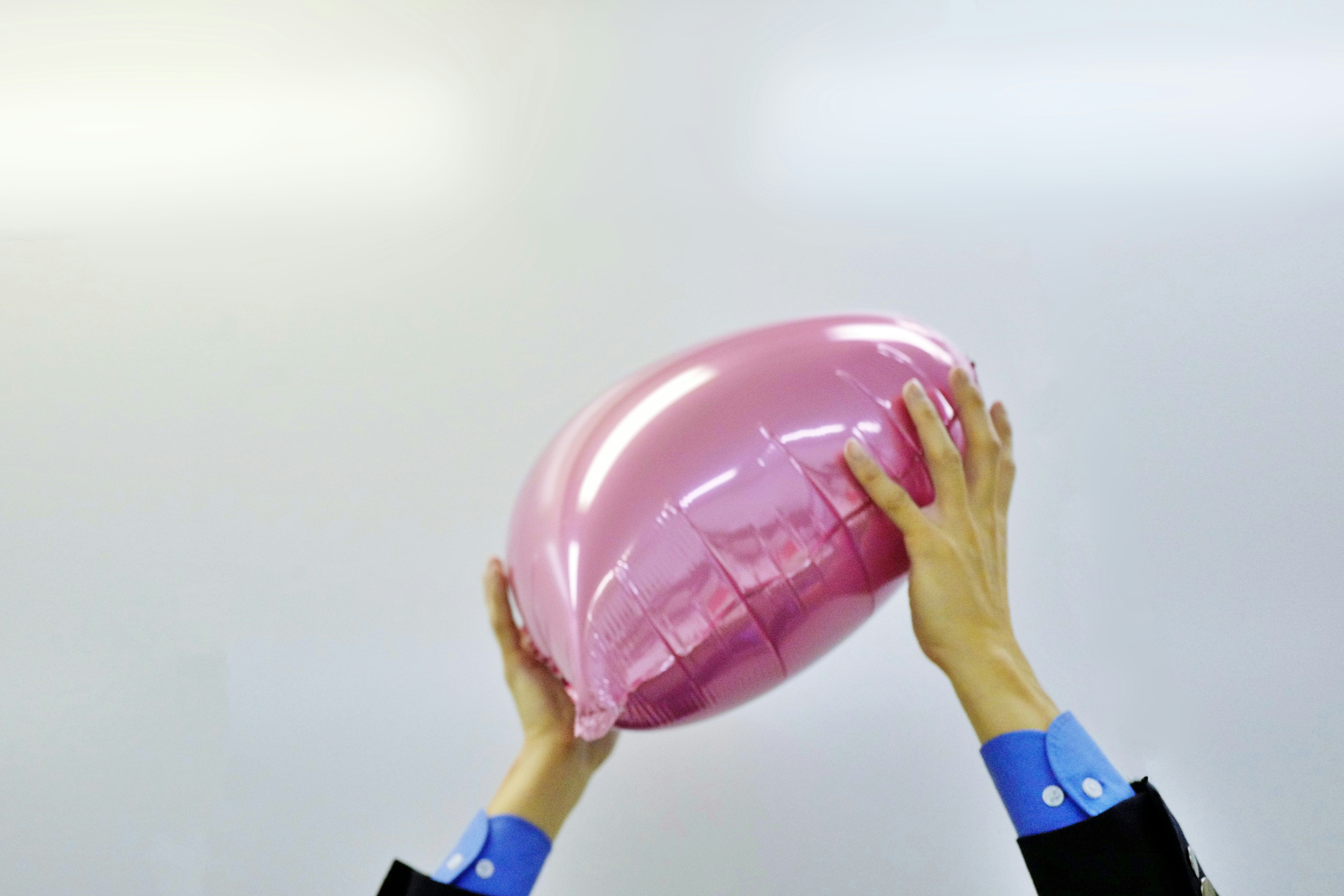 Eine Person hält ein großes, ballonartiges Objekt in Pink